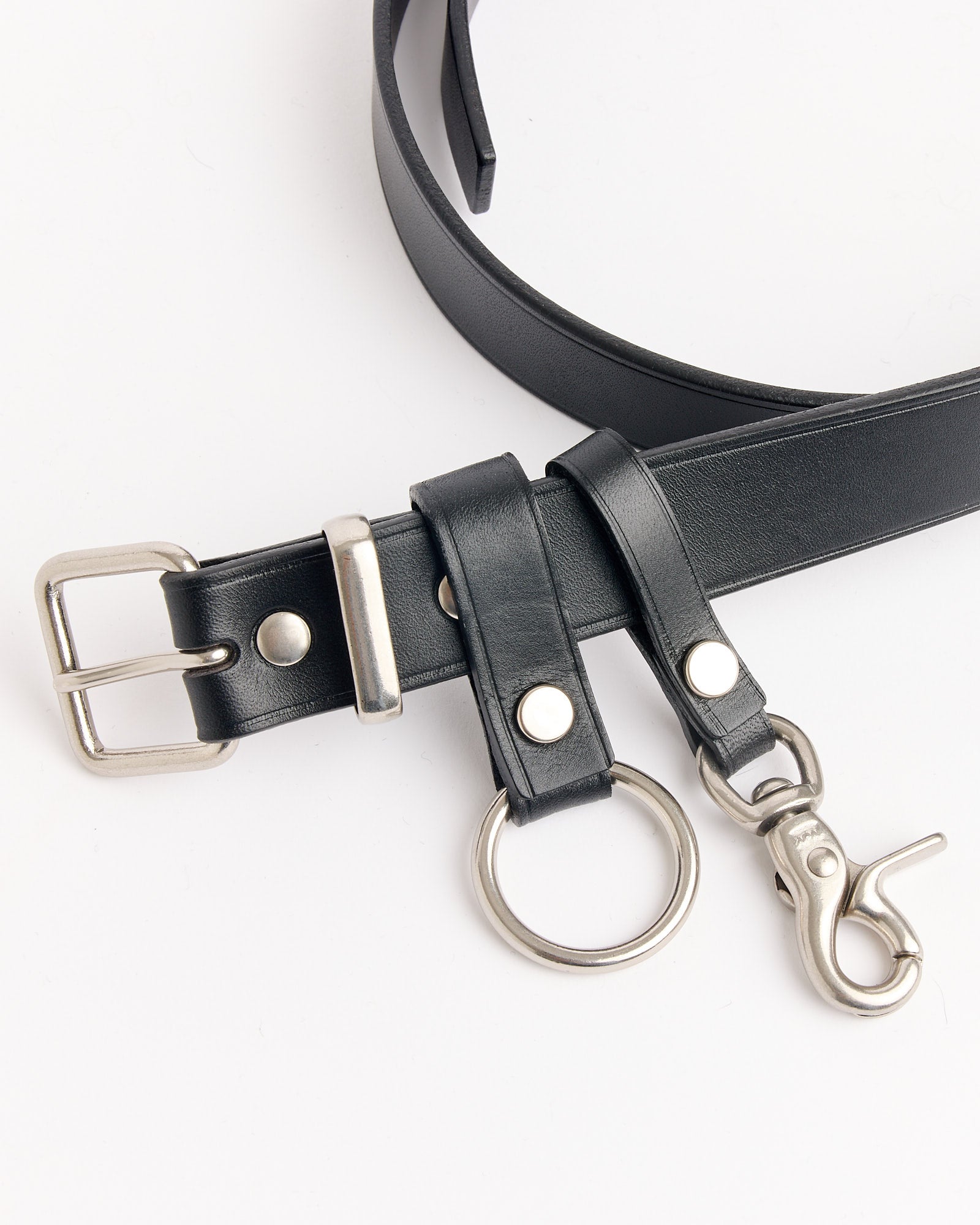The Comme Des Garçons Homme 301 Belt in Black features a leather strap, silver buckle, metal ring, and clasp attachment. Laid flat on a white surface. For sizing or fit questions, our online chat is ready to assist you.