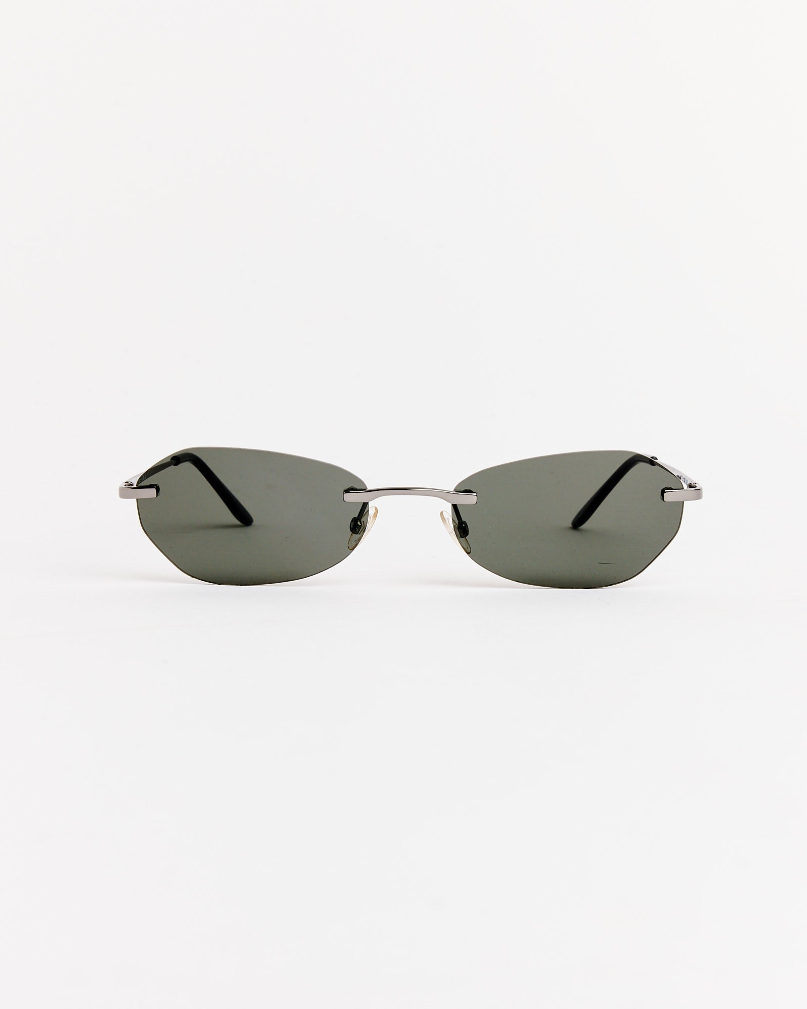 The Adorable Sunglasses in Trinity Black by Our Legacy, featuring rimless dark lenses and thin metal arms, are shown against a plain white background.