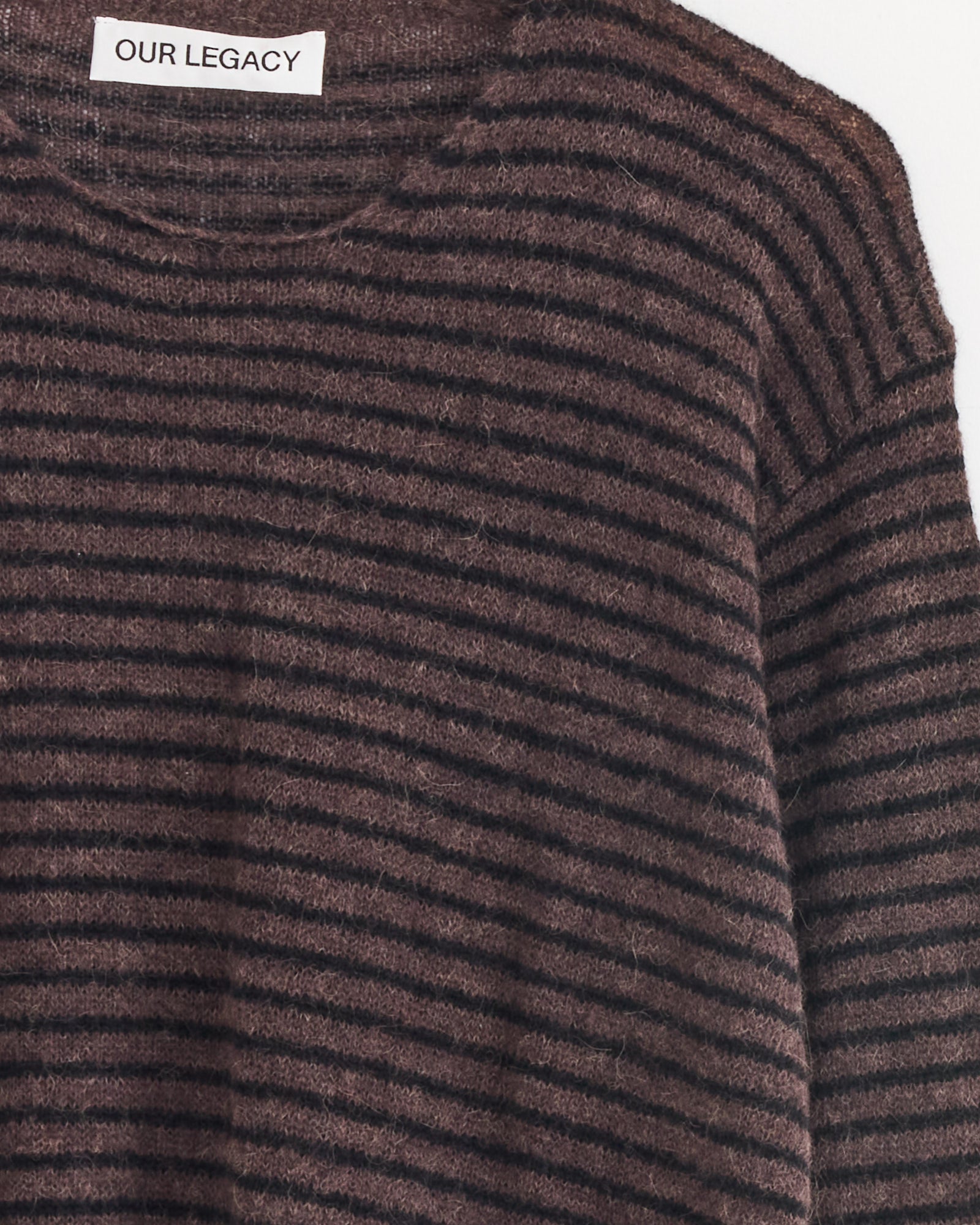 A close-up of the Our Legacy Rigid Popover Sweater in Dirt Stripe, featuring brown and black stripes, a round neckline, and an inner collar with a white OUR LEGACY label.