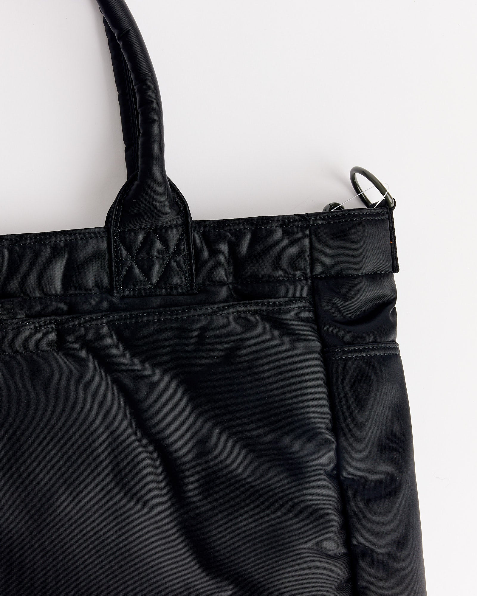 A close-up of the top corner of the Porter Tanker Tote Bag in Black, featuring padded handles and silver hardware, photographed against a white background.