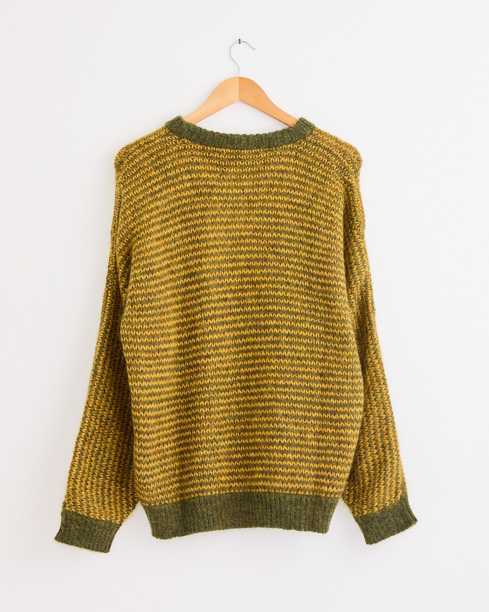 The You Must Create Black Palm Knit in Yellow/Green is shown from the back on a wooden hanger against a white wall. For fit or sizing questions, contact us via our online chat.