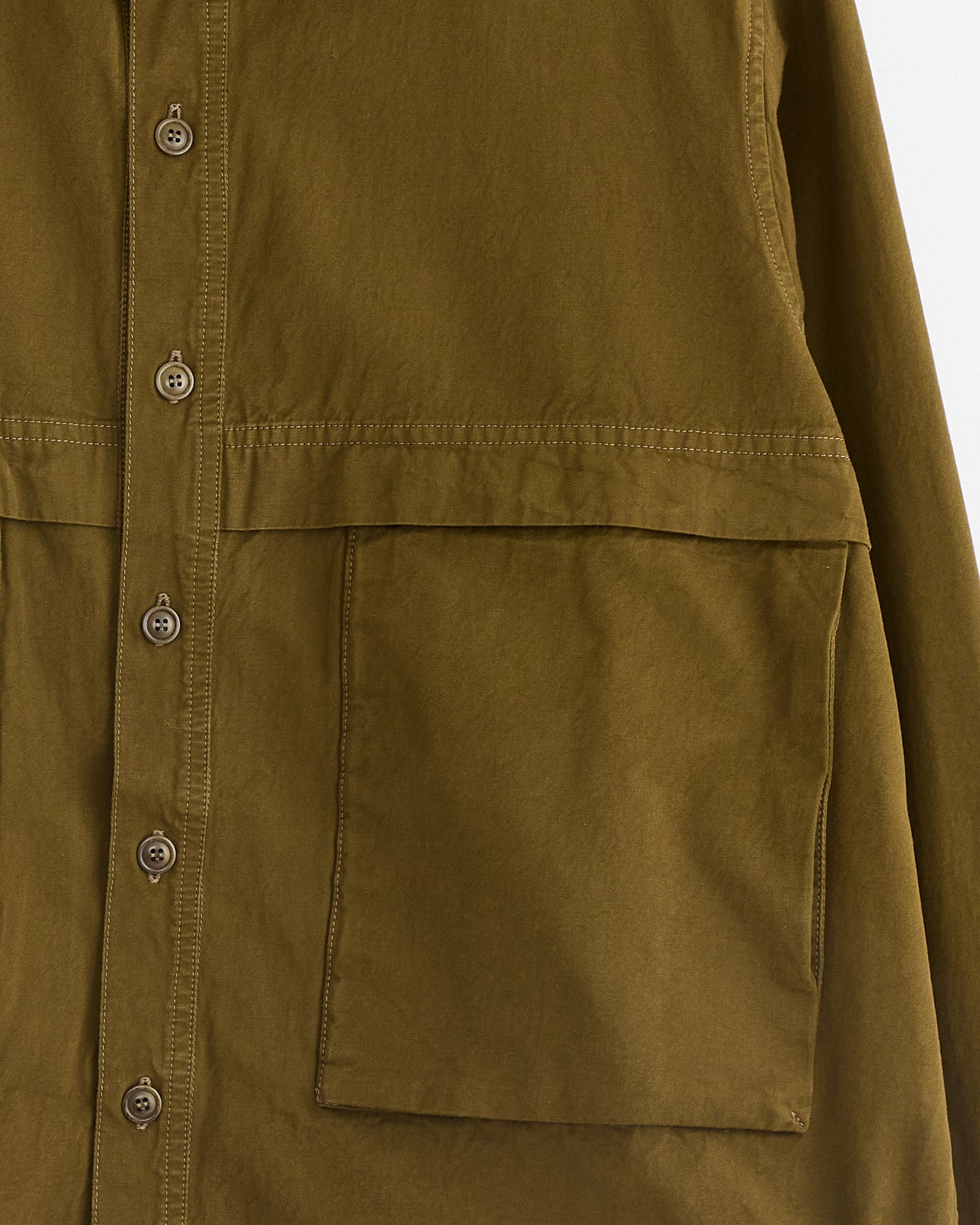 Close-up of the Casey Casey Fabu Shirt in Green Lake—a 100% cotton button-up with multiple buttons and two large front pockets, featuring visible stitching.