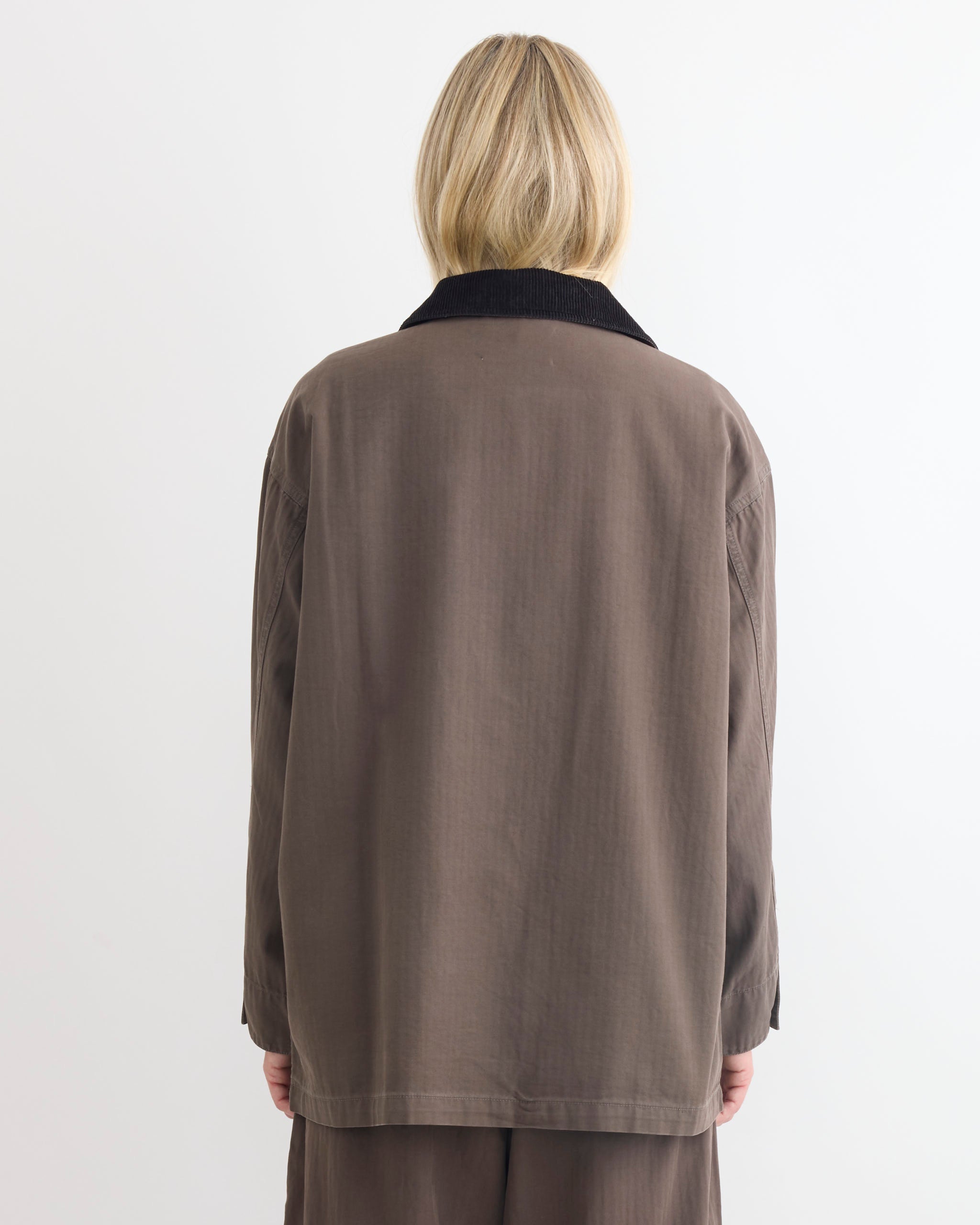A person with blonde hair, seen from behind, wears the Shaina Mote Painter Coat in Ermine with a corduroy collar against a plain white background.