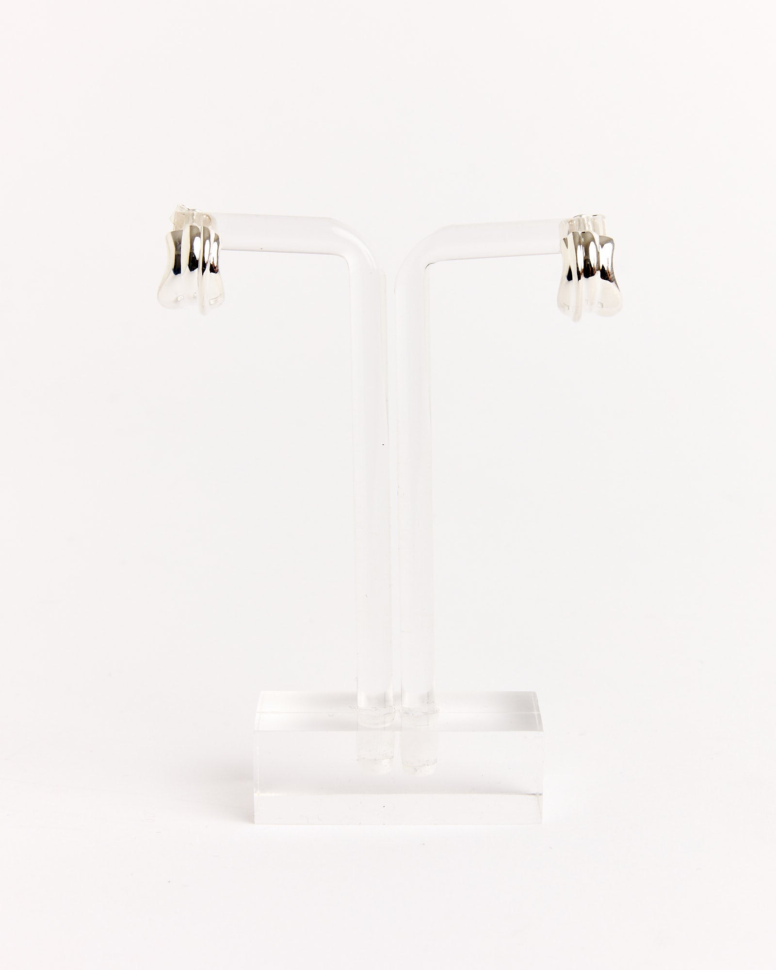 A pair of Recycled Silver Earrings by Completedworks, shown on a transparent T-shaped stand against a plain white background.