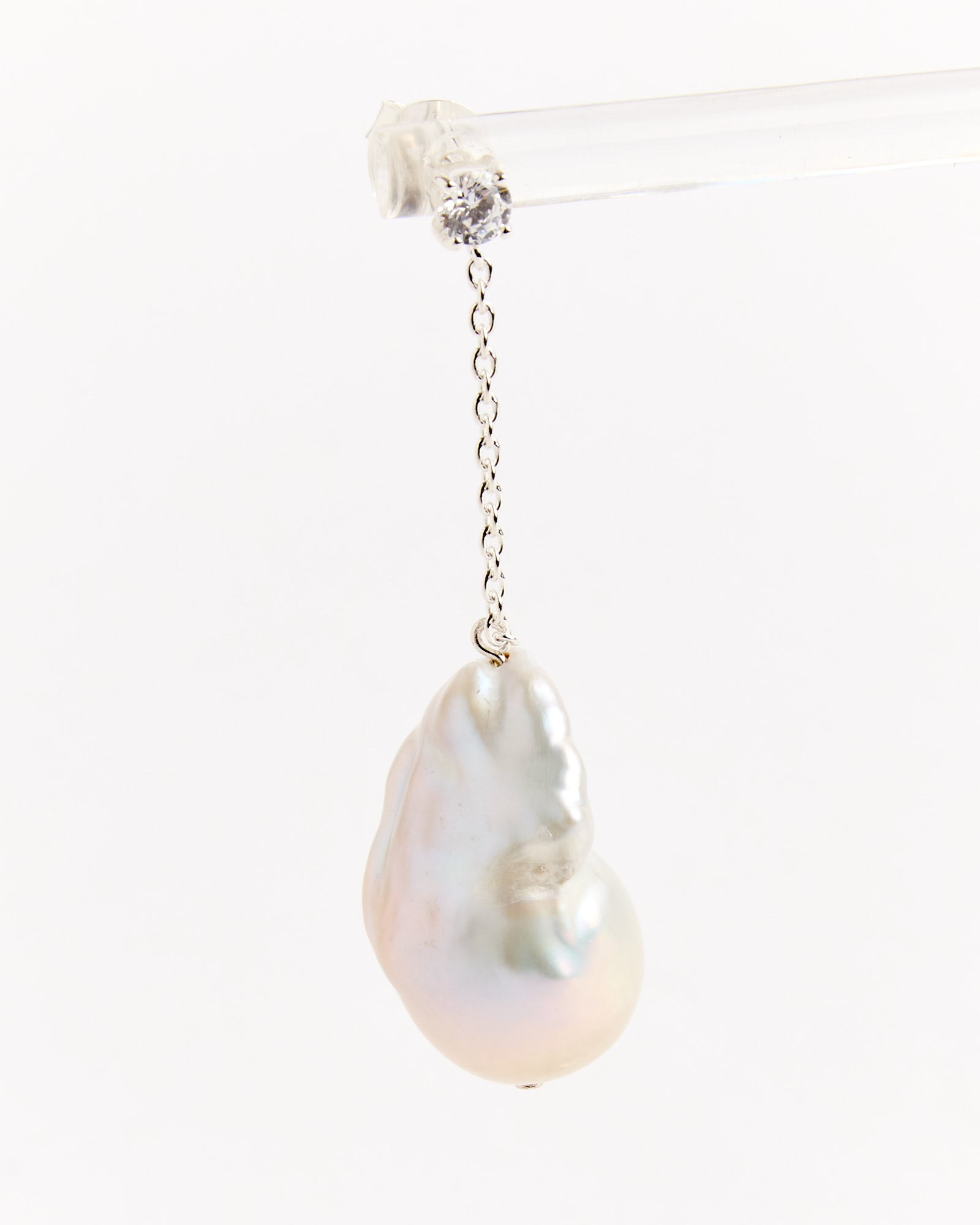 The Completedworks Recycled Silver Baroque Pearl CZ Earrings feature a single baroque pearl on a delicate recycled silver-plated chain with a round cubic zirconia, displayed against a plain white background.