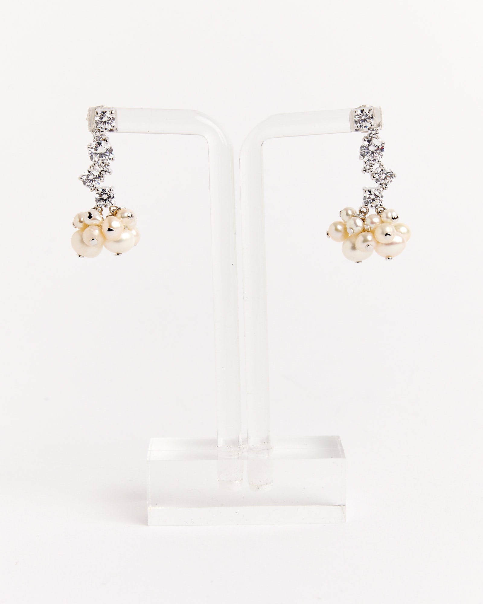 The Completedworks Recycled Silver Pearl Cluster CZ Earrings feature clusters of white pearls and silver beads with sparkling clear stones. For sizing questions, contact us via online chat. Shown on a clear stand against a white background.
