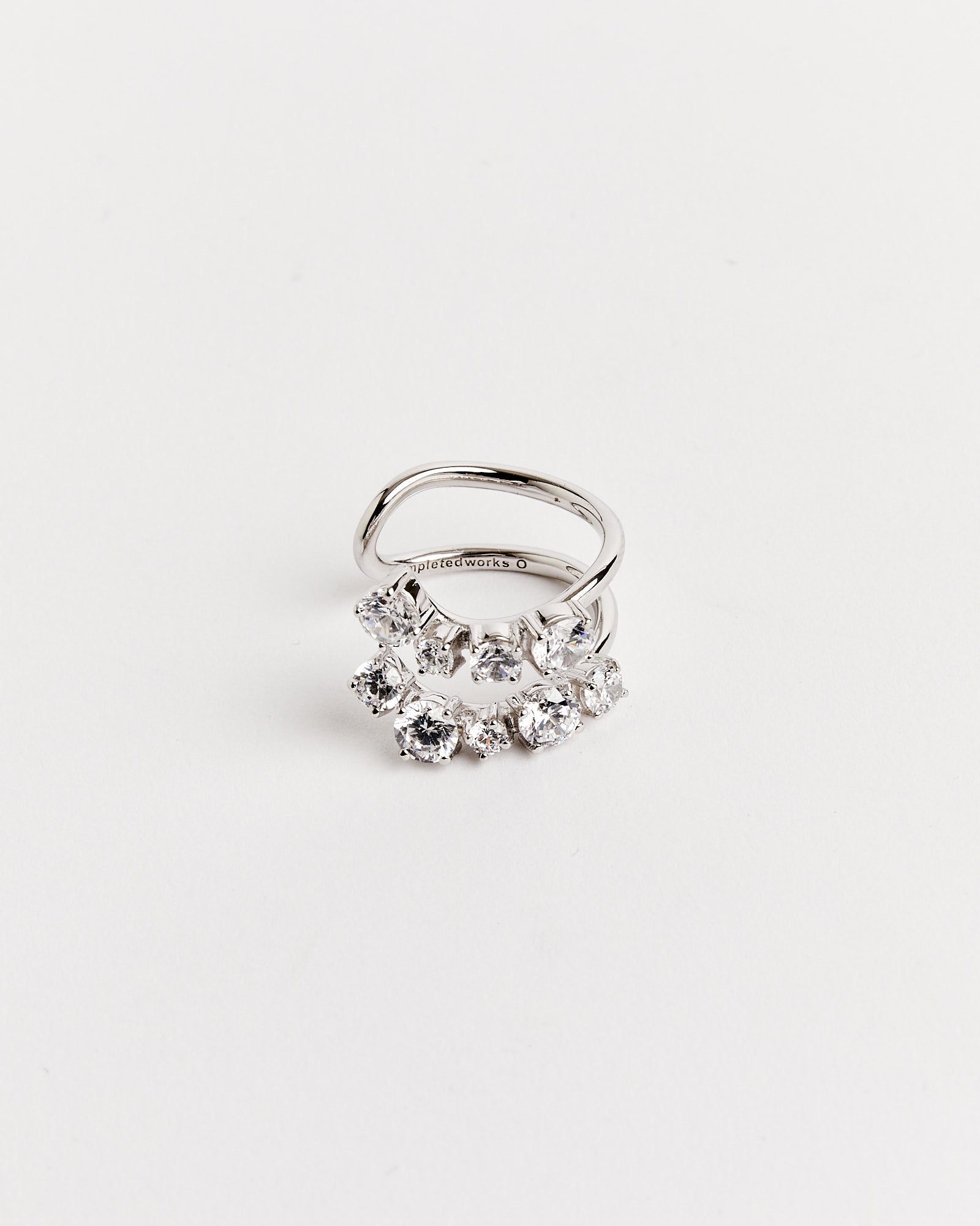 The Completedworks Recycled Silver Myth CZ Ring features two overlapping bands with clustered, sparkling gemstones. Shown on a white background. For fit or sizing questions, our online chat is here to help.