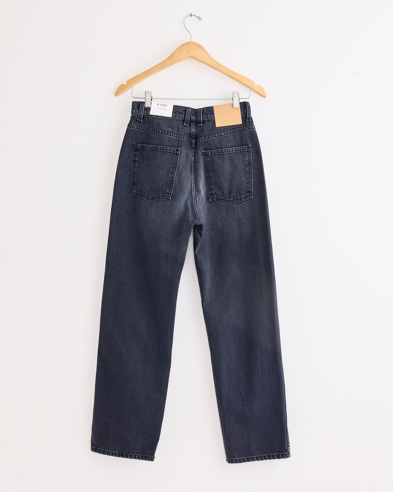 A model wears the B Sides Plein Jean in Stil Black, a pair of relaxed straight jeans.