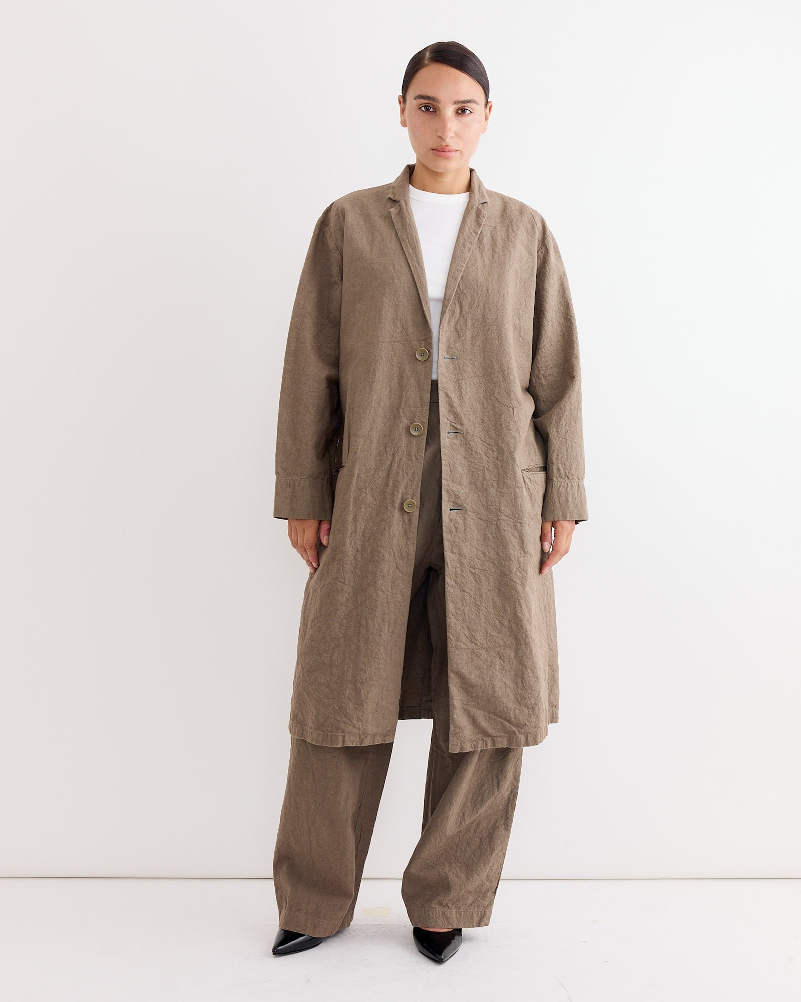 A woman wears the Crinkled Coat in Khaki by Black Crane, crafted from Japanese linen.