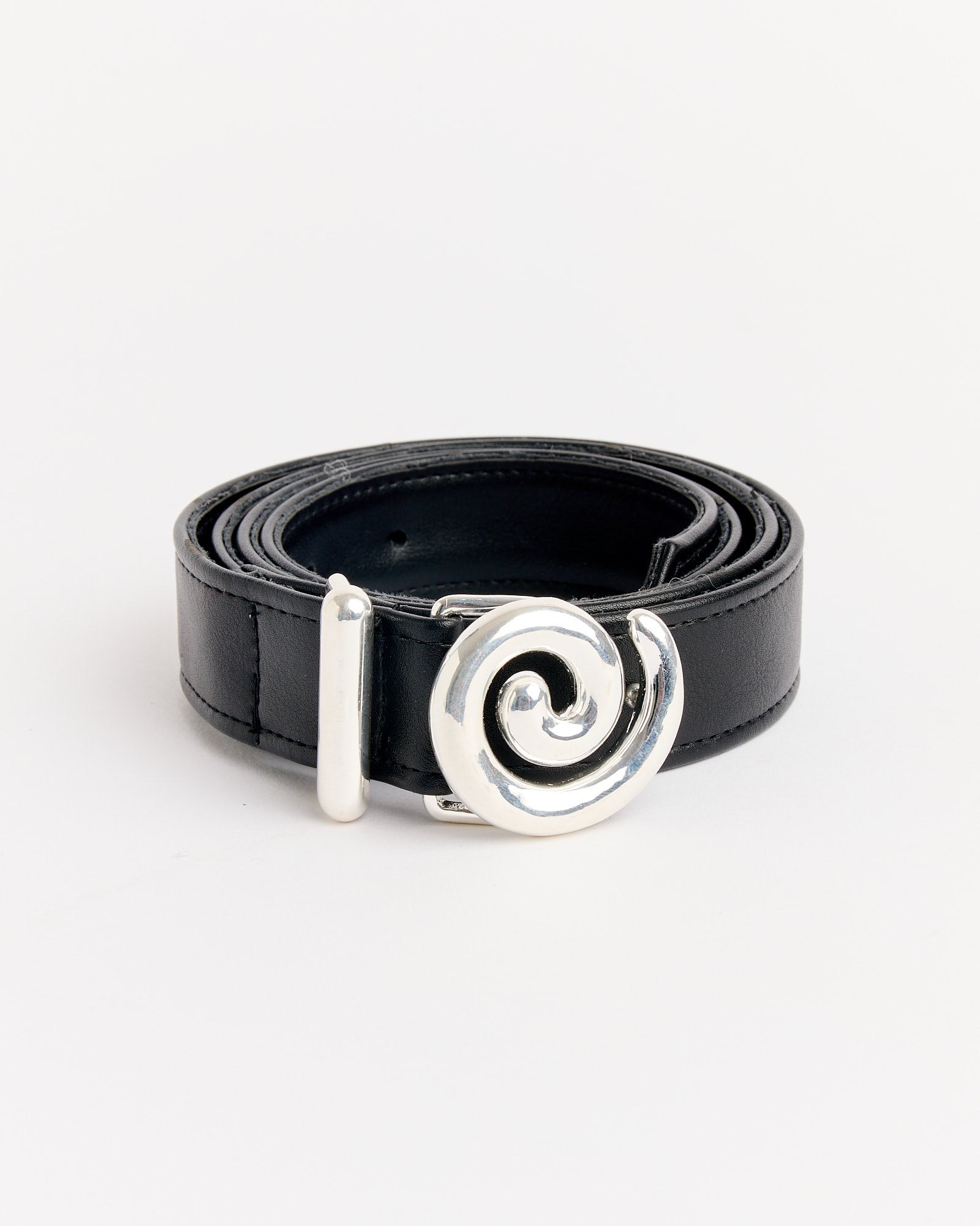 The NOMIA Faux Leather Spiral Buckle Belt in Silver is coiled neatly, showing off its bold spiral buckle, against a white background. Sizing help is available online to ensure the perfect fit.