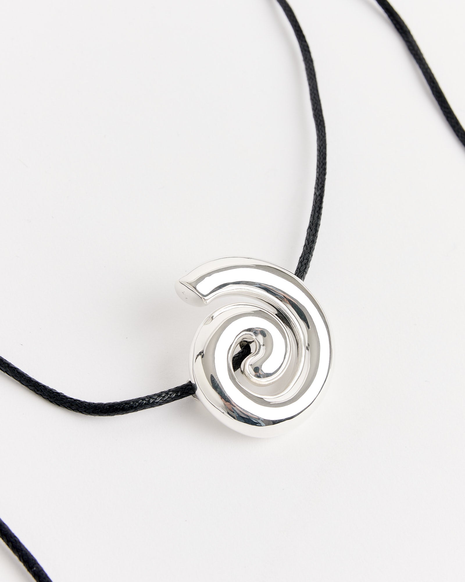 The NOMIA Spiral Cord Necklace features a shiny silver spiral pendant on a thin black cord, shown against a white background. For sizing or fit questions, please contact us through our online chat.