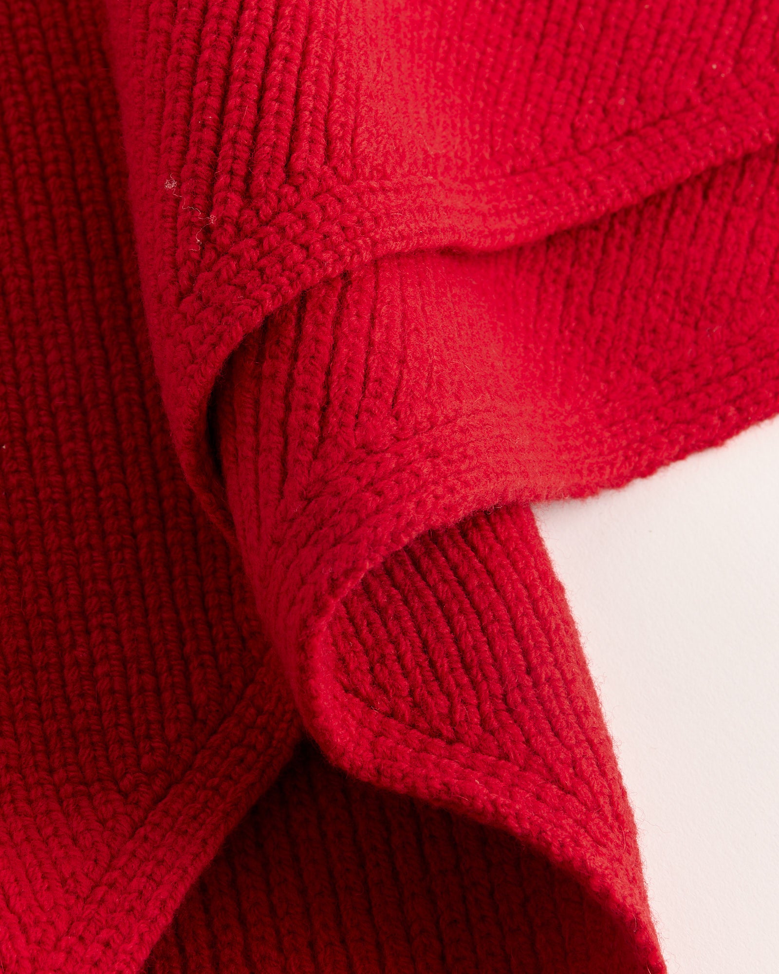 Close-up of Studio Nicholson's Pythagoras Scarf in Crimson, showing textured merino wool with visible ribbed patterns, folded to highlight both top and underside. Set against a white background.