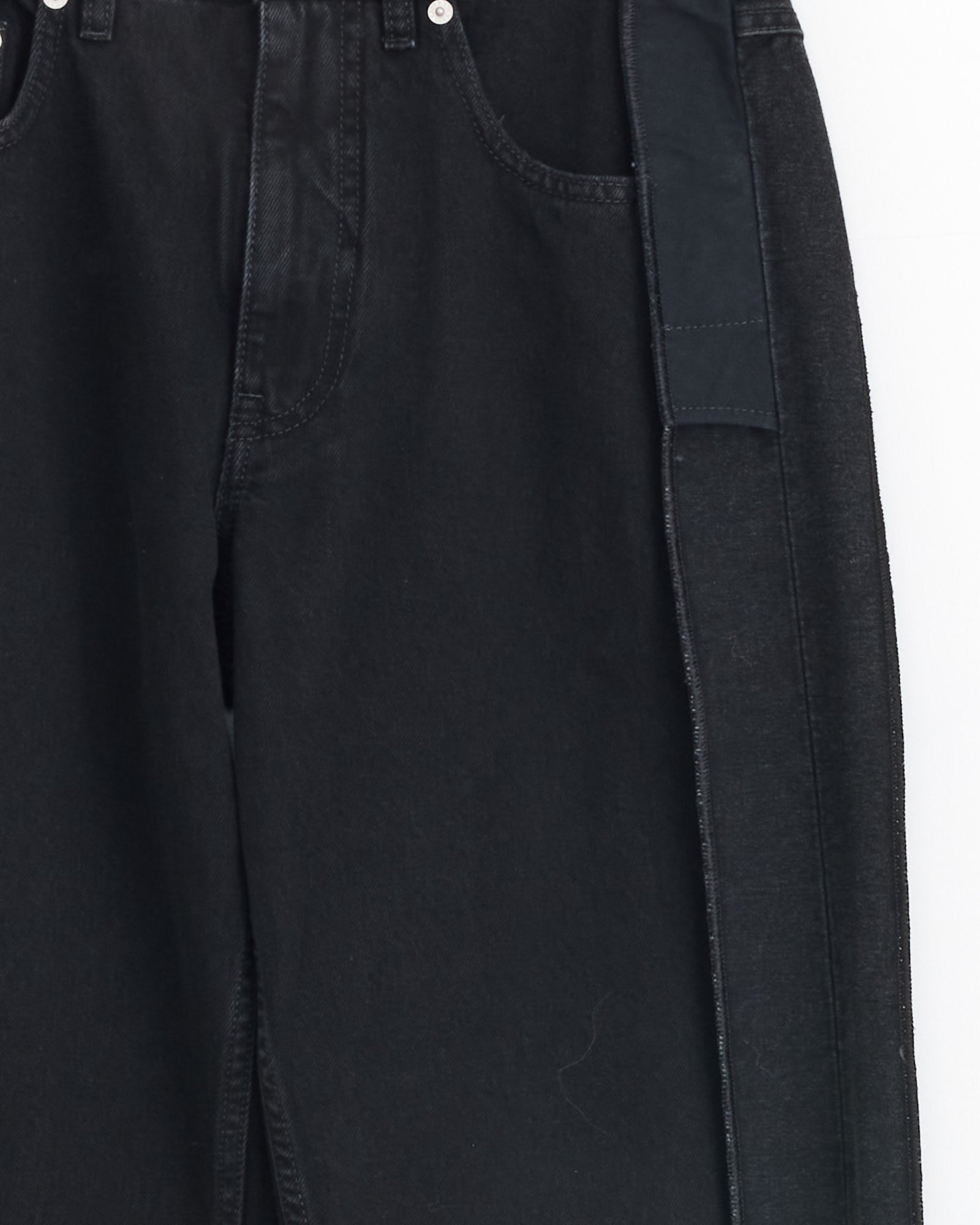 Close-up of the MM6 Maison Margiela 5 Pockets Pant in Black, made from cotton denim with front pockets, a contrasting fabric panel along the right seam for a sculptural look, visible stitching, and a metal rivet near the pocket.
