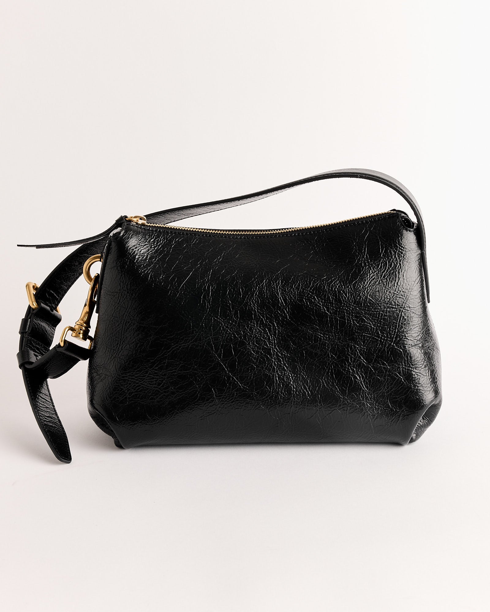 The Grip Bag by Dries Van Noten is a small black leather wristlet with a gold zipper and textured, slightly glossy finish, made in Italy and shown against a plain white background.