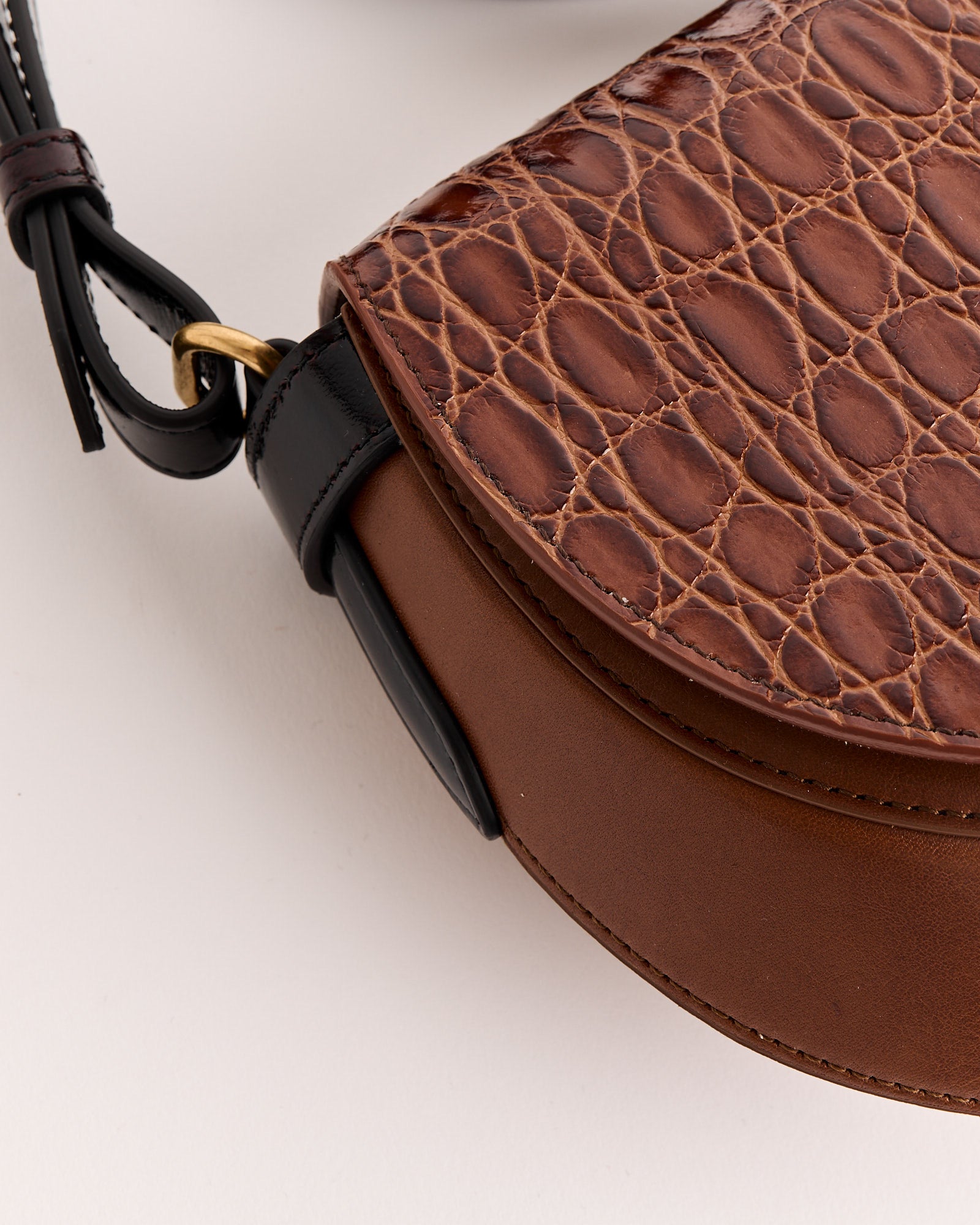 Close-up of the Dries Van Noten Arc Bag featuring a croc-embossed leather flap, smooth leather body, black strap attachment, and gold ring hardware.