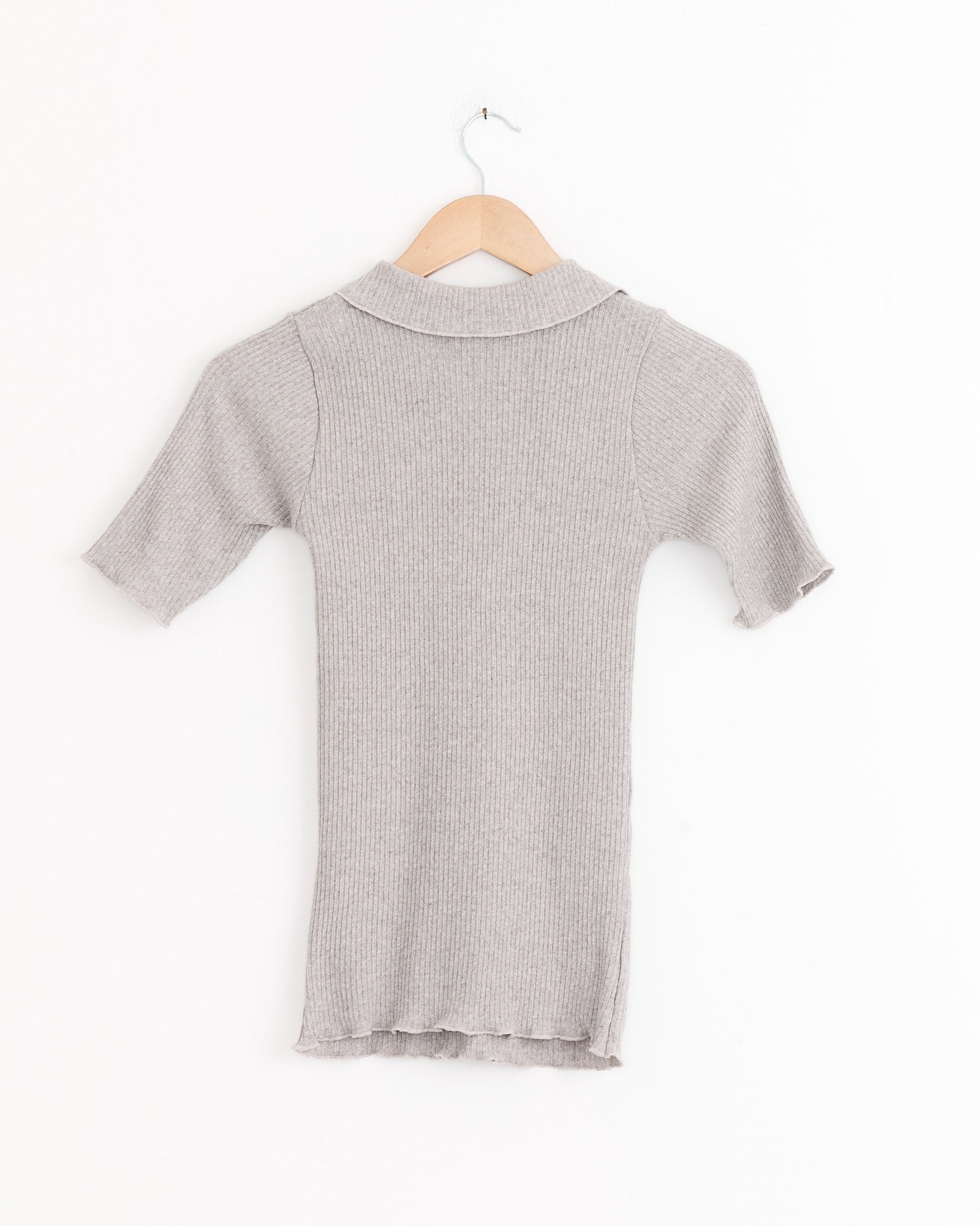 The Baserange Dual Polo in Grey Melange, a light gray short-sleeve ribbed knit dress with a collar, hangs on a wooden hanger against a plain white background.
