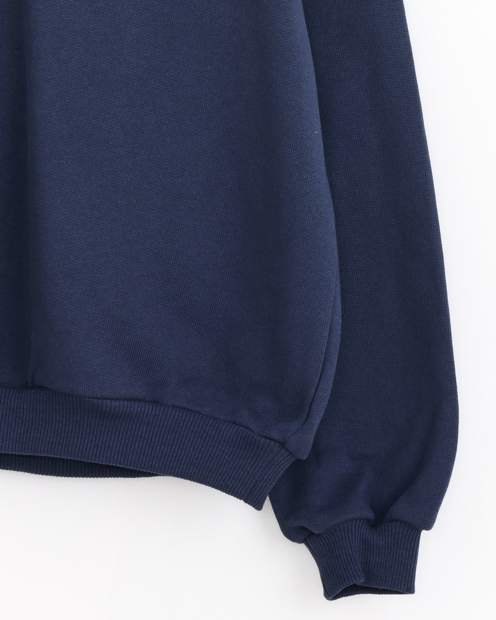 A close-up of the Baserange Rim Raglan Sweatshirt in Echo Blue, crafted from organic cotton, highlights its ribbed hem and cuffs with long sleeves against a plain white background.