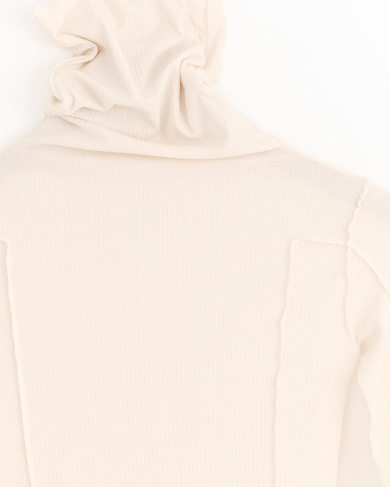Close-up of the Baserange Omato Turtleneck in Off White, showing the collar and shoulder seams of this organic cotton turtleneck with a soft, ribbed texture against a white background.