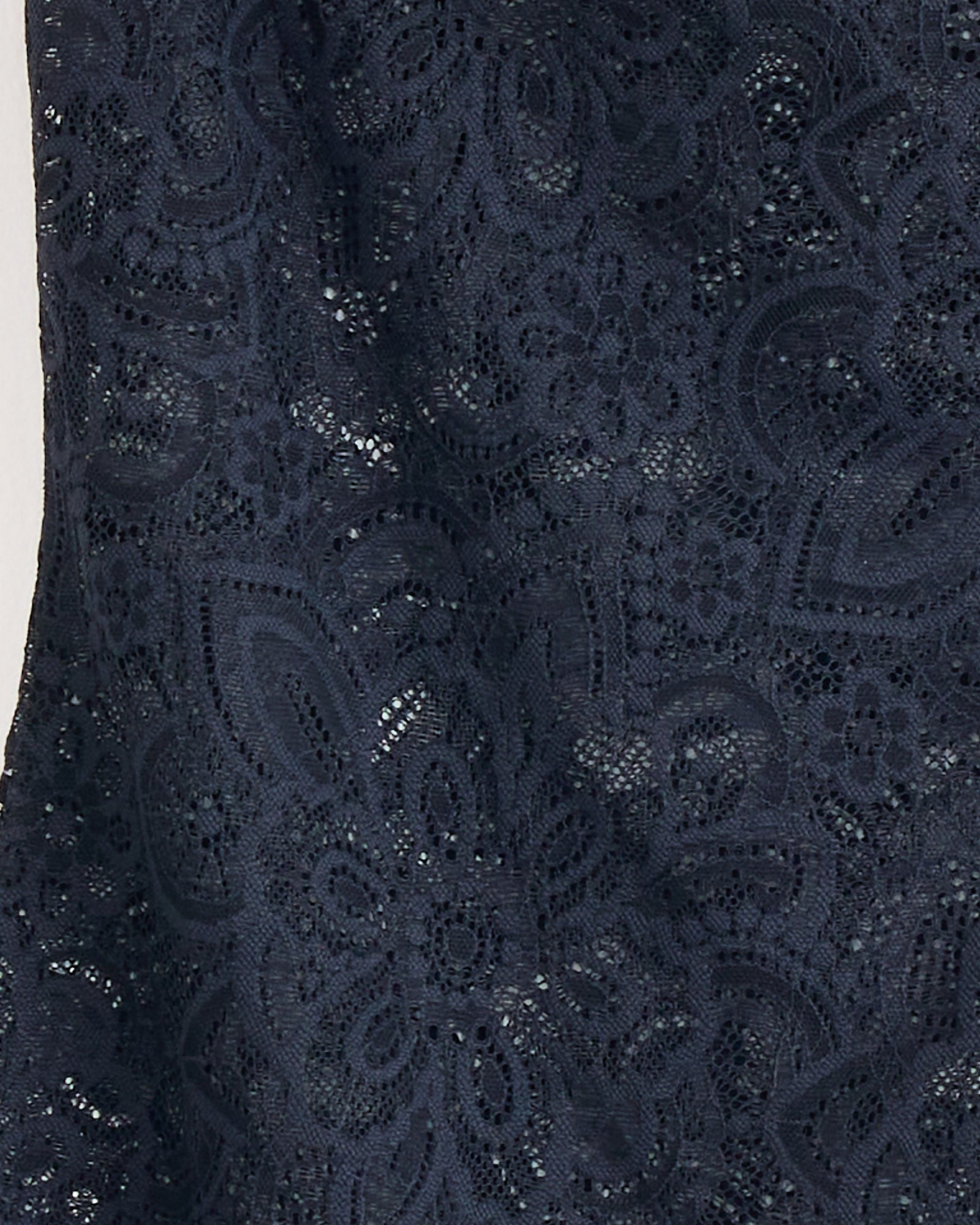 Close-up of Beaufille's Anise Blouse in Black, featuring dark navy blue stretch lace with a detailed floral and geometric pattern, highlighting its fine texture.