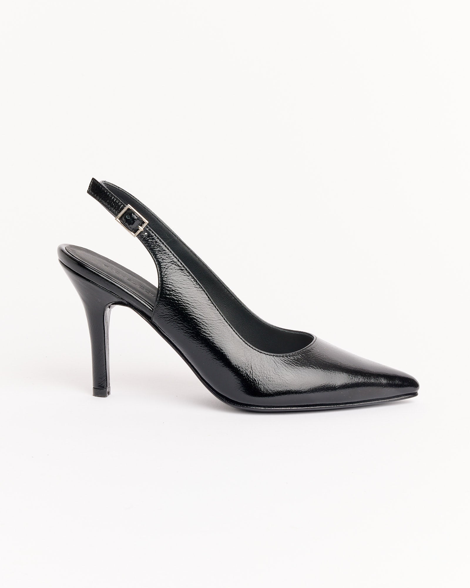 The Cheke Sling Back Heel in Black by Rachel Comey features black patent leather, a pointed toe, and an adjustable ankle strap, shown on a white background.