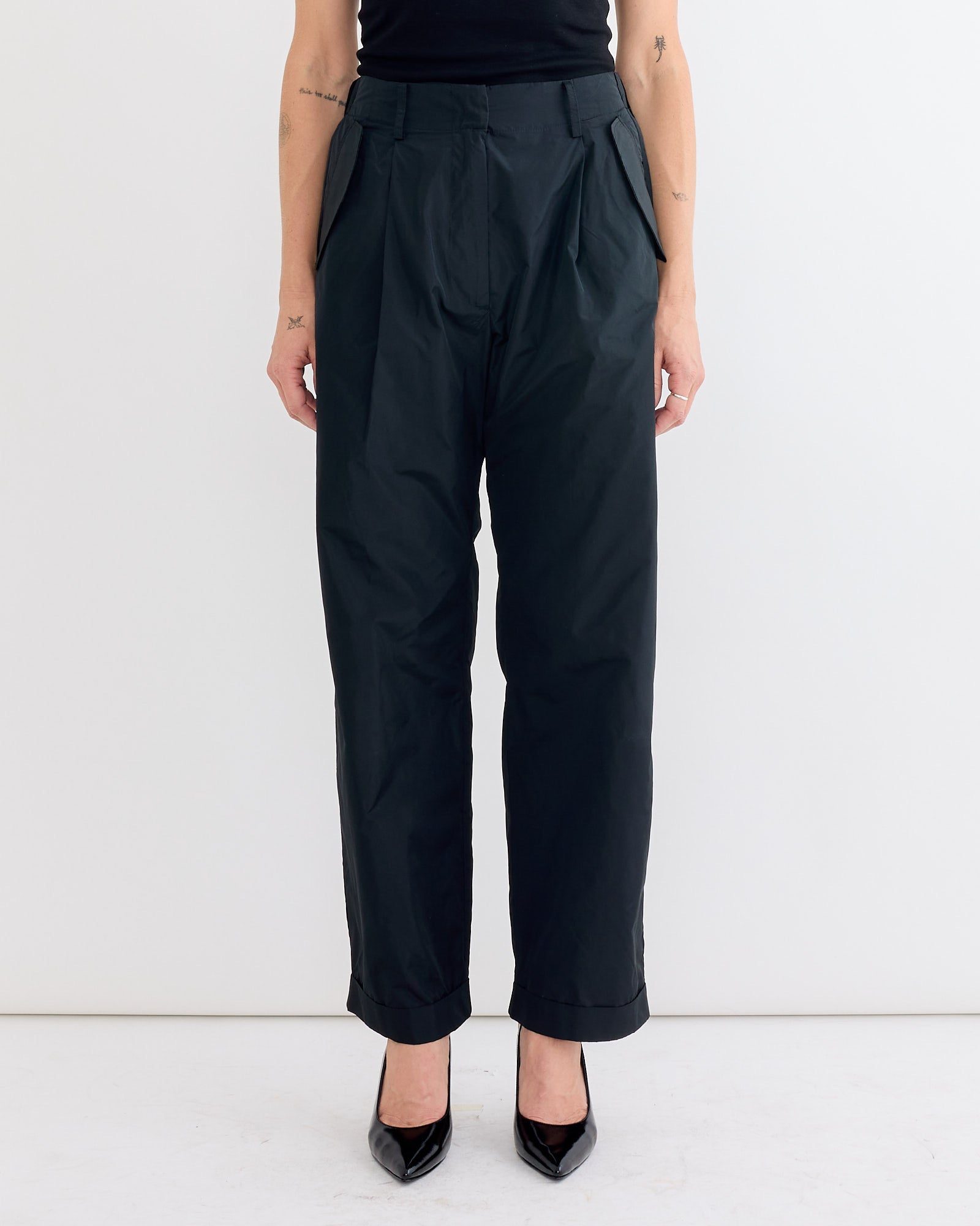 A model, shown from shoulders down, wears the Rachel Comey Bending Pant in Black with black pointed-toe heels against a plain white background.