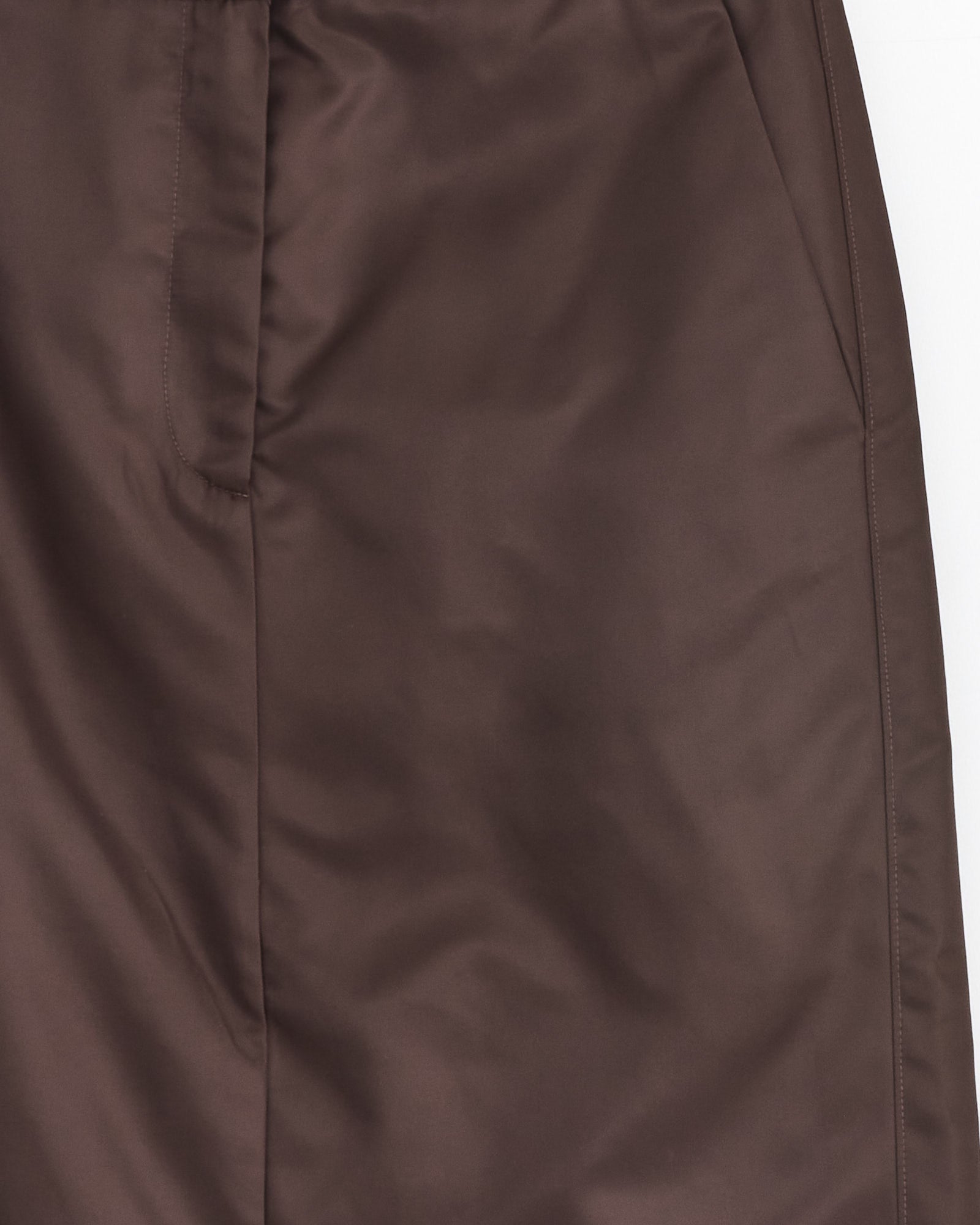 Close-up of the Tibi Eco Nylon Midi Trouser in Skirt Brown, showcasing smooth fabric, a visible side pocket, and an edge stitched seam.