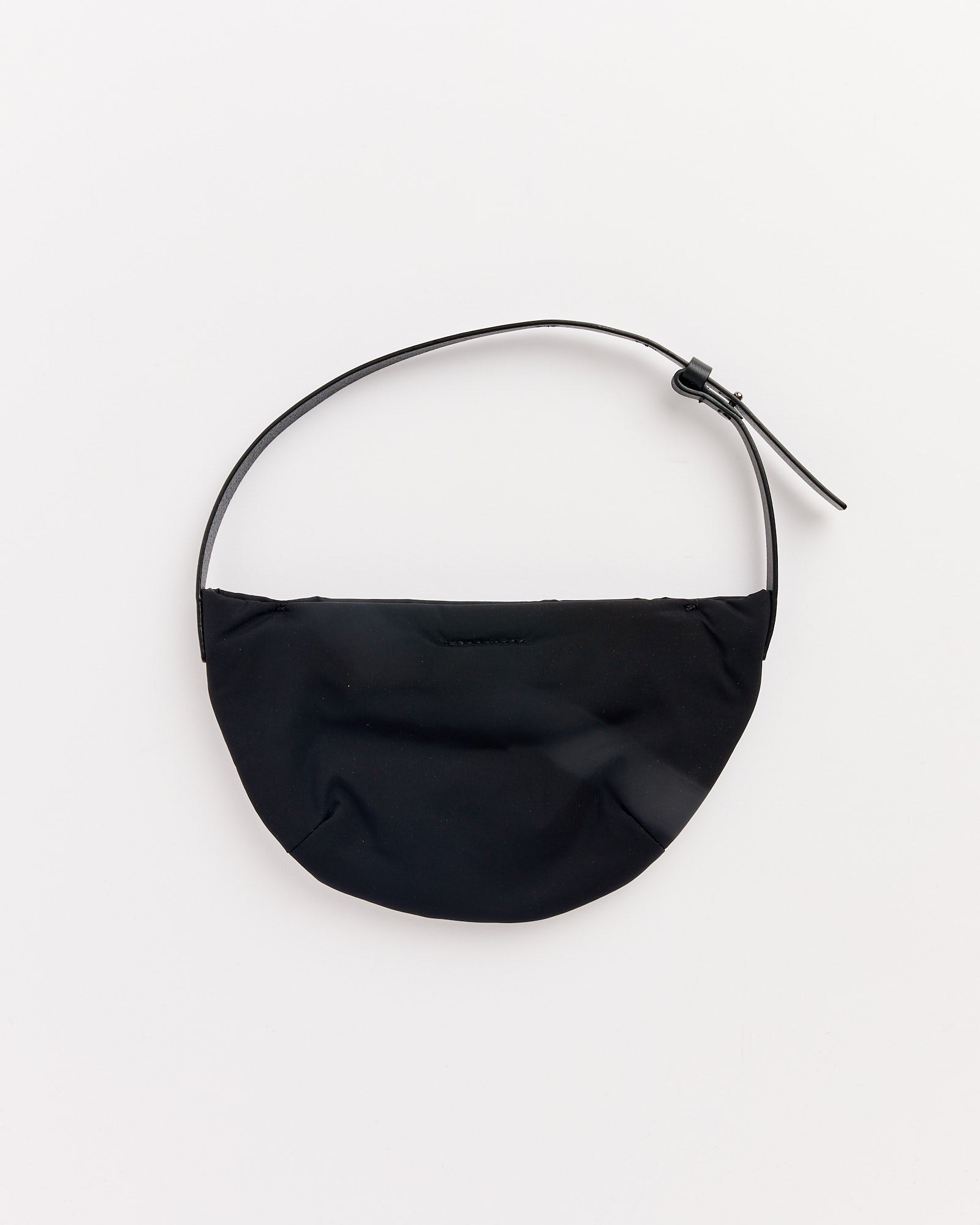 The Amomento Mini Padded Bag in Black is a small, crescent-shaped taffeta bag with a curved strap and buckle, shown laid flat on a white background.