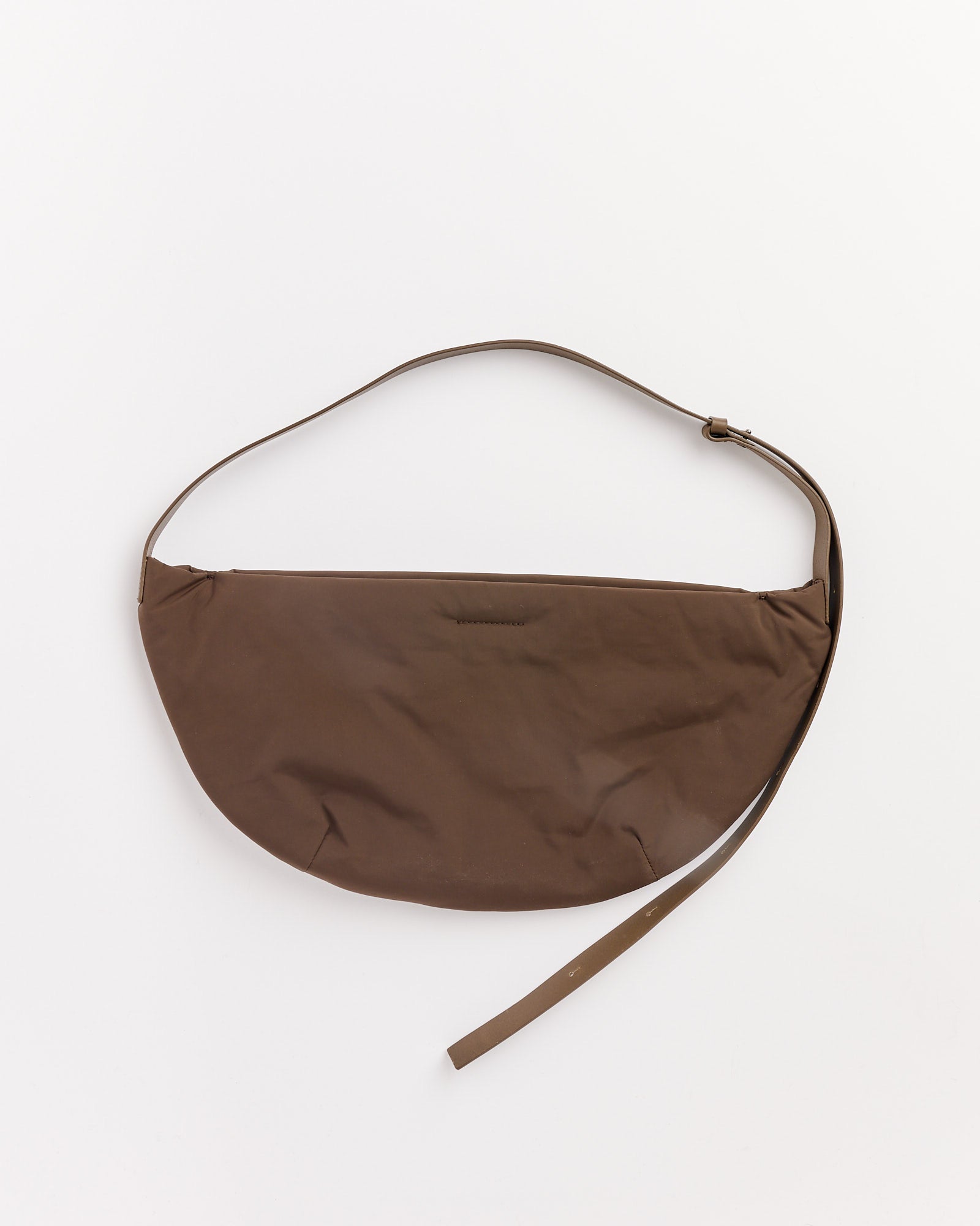 The Amomento Small Padded Bag in brown, featuring a crescent shape, taffeta material, leather strap, and adjustable length, is shown against a plain white background.