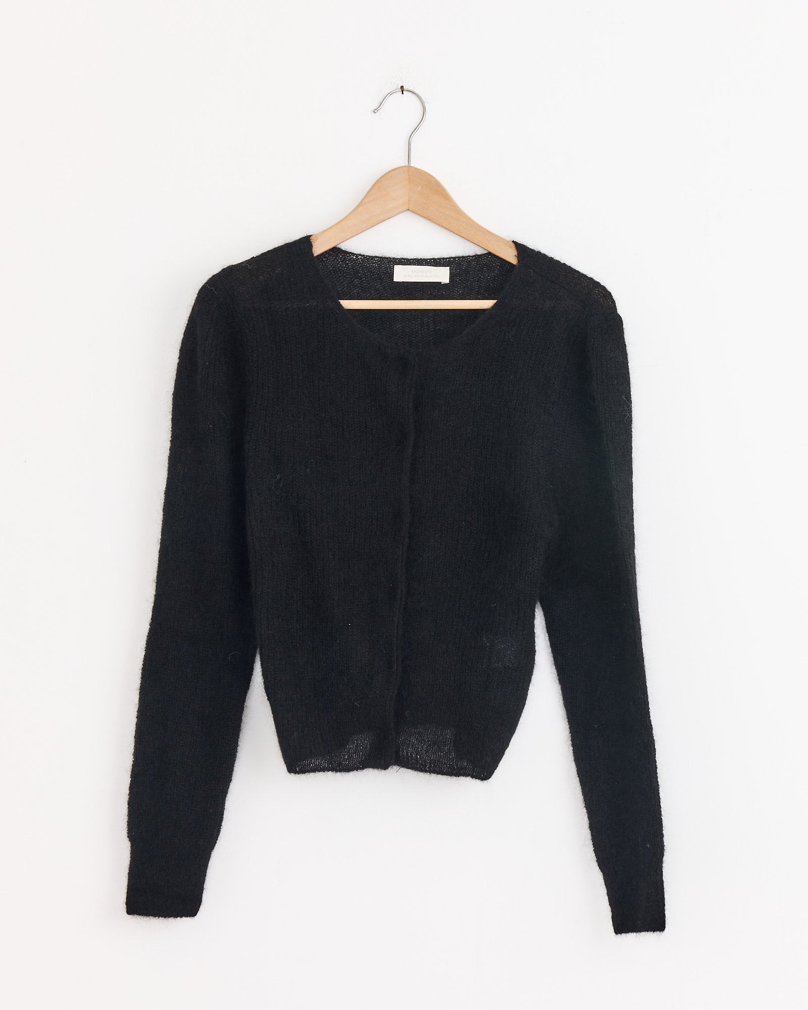 The Amomento Round Neck Sheet Cardigan in Black, a long-sleeve mohair-blend style, is displayed on a wooden hanger against a plain white background.