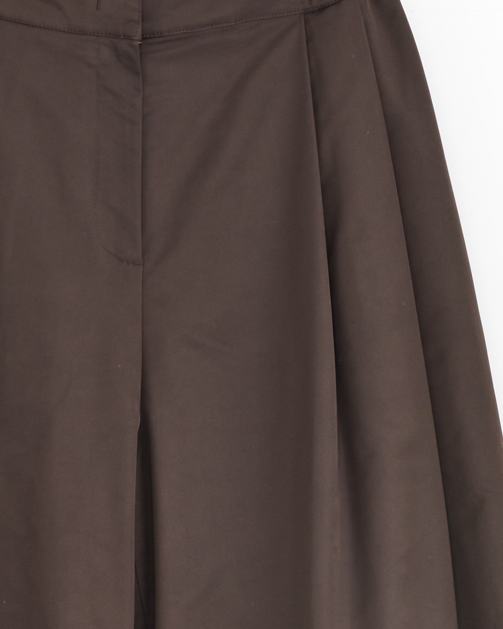 Close-up of Amomento’s Two Tuck Balloon Pant in Dark Brown, featuring wide legs, pleats, and an elastic waistband. The smooth fabric and detailed seams stand out against a white background.