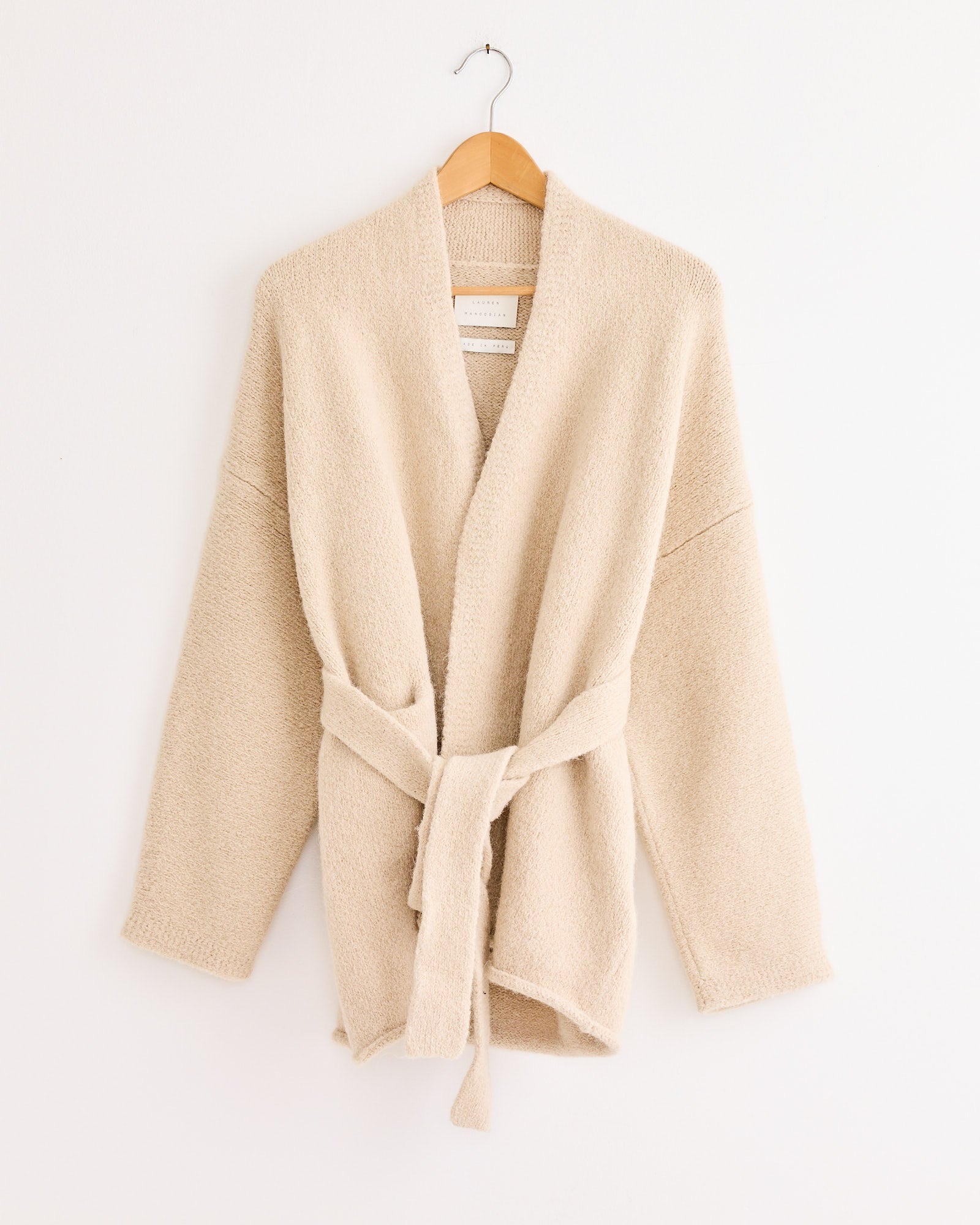 The Lauren Manoogian Coto Cardigan, a beige hand-loomed knit robe, offers cozy comfort and careful craftsmanship.