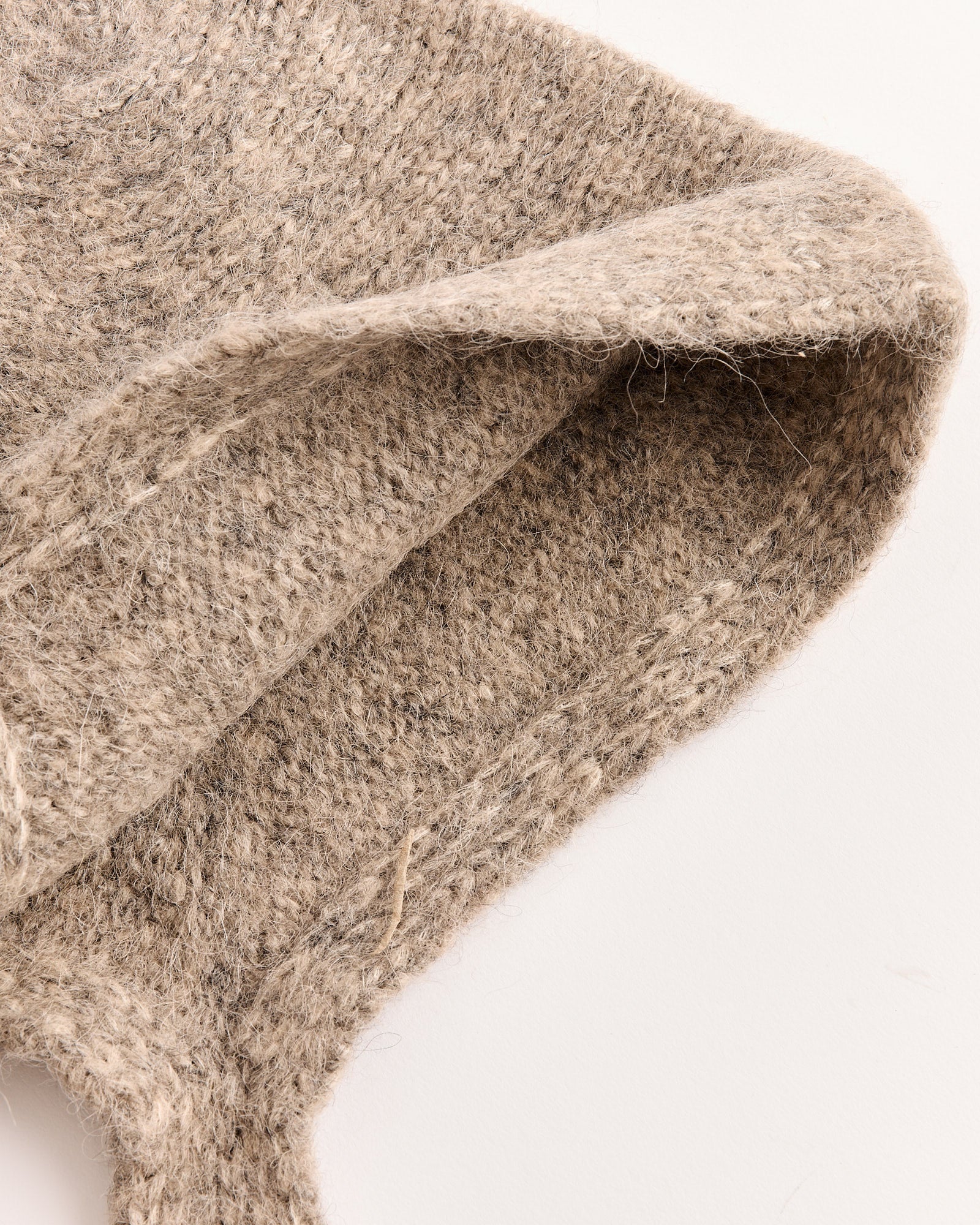 Close-up of the Lauren Manoogian Loft Bonnet in Ash, showing its knitted, textured woolen fabric in a soft neutral tone, folded to highlight its thickness and fibers, set against a plain white background.