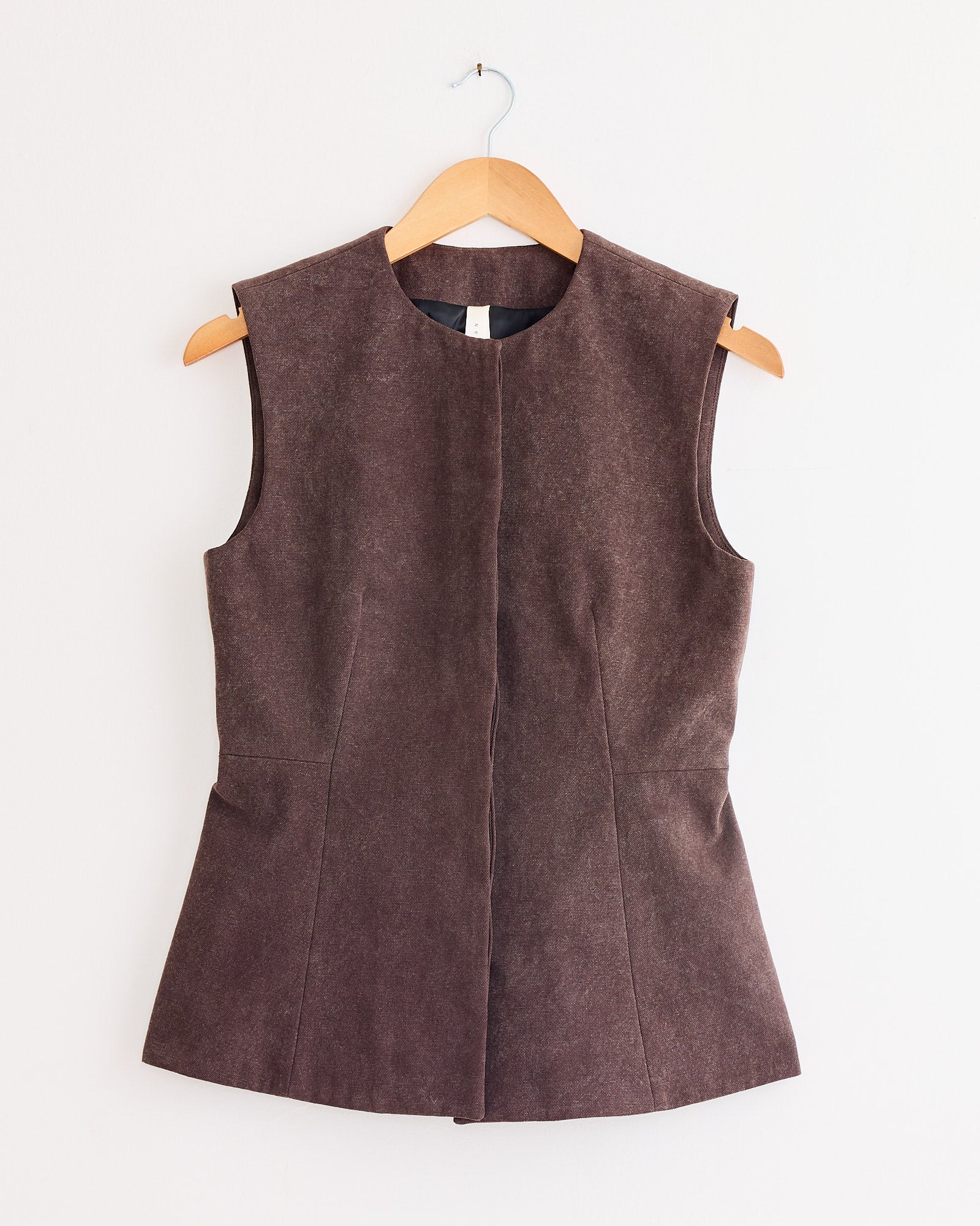 Lauren Manoogian Canvas Bodice in Washed Soil—sleeveless with a structured, tailored fit—displayed on a wooden hanger against a plain white wall.
