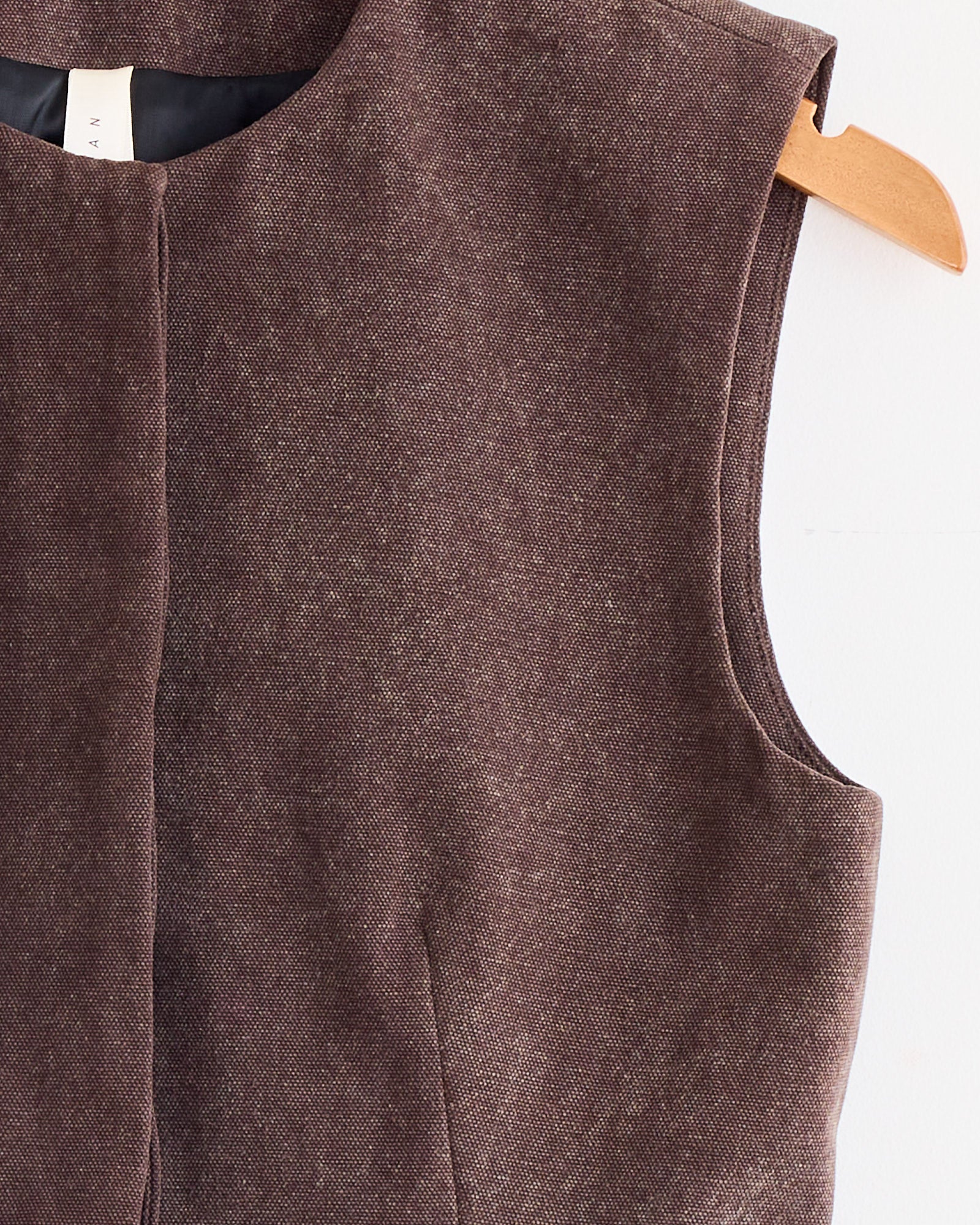 Close-up of the Lauren Manoogian Canvas Bodice in Washed Soil, a sleeveless brown textured dress with a hand-dyed cotton bodice, round neckline, structured silhouette, and front hidden zipper, displayed on a wooden hanger against a white background.