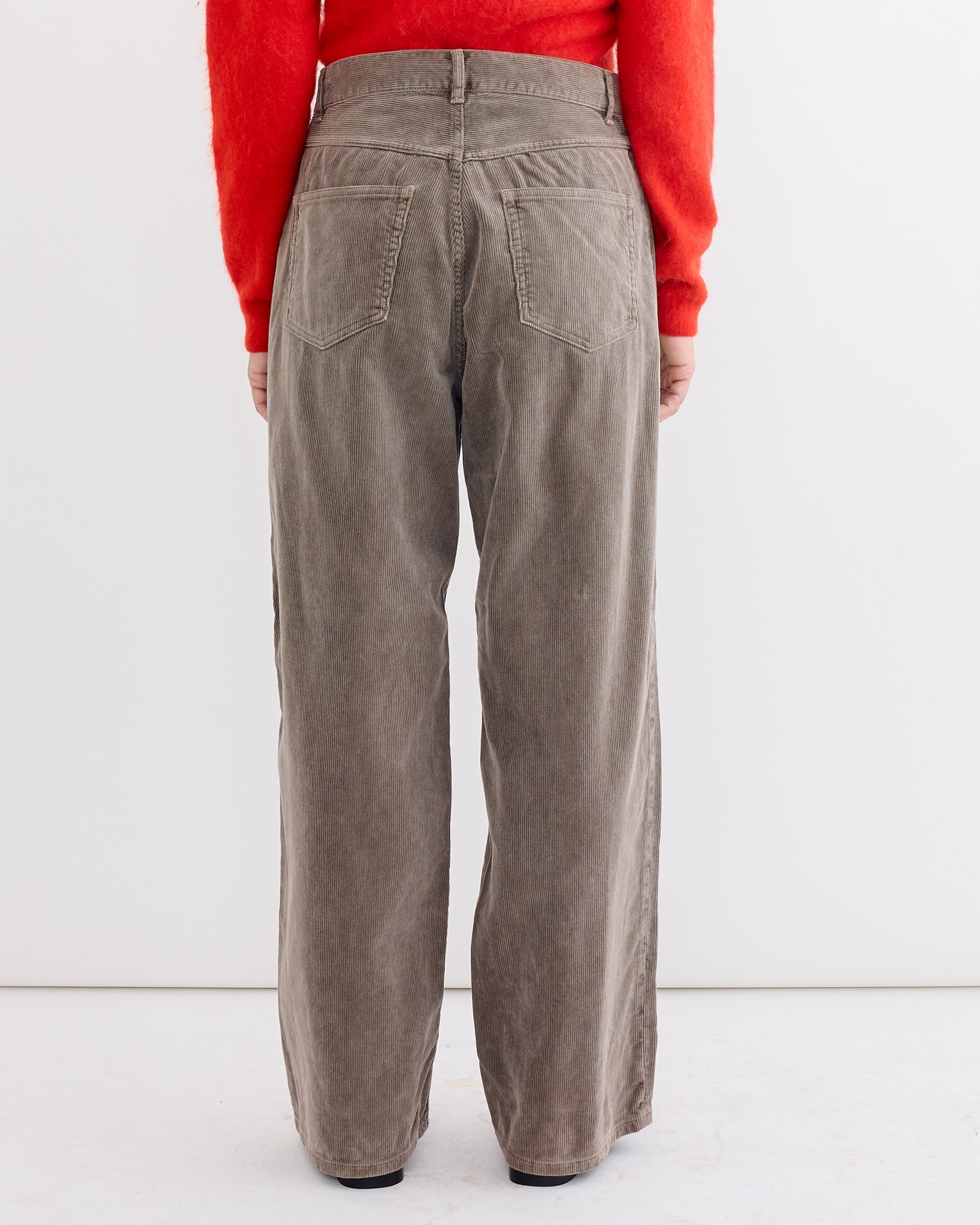 A person wearing a red sweater and Auralee Corduroy Wide 5P Pant in Olive Brown.