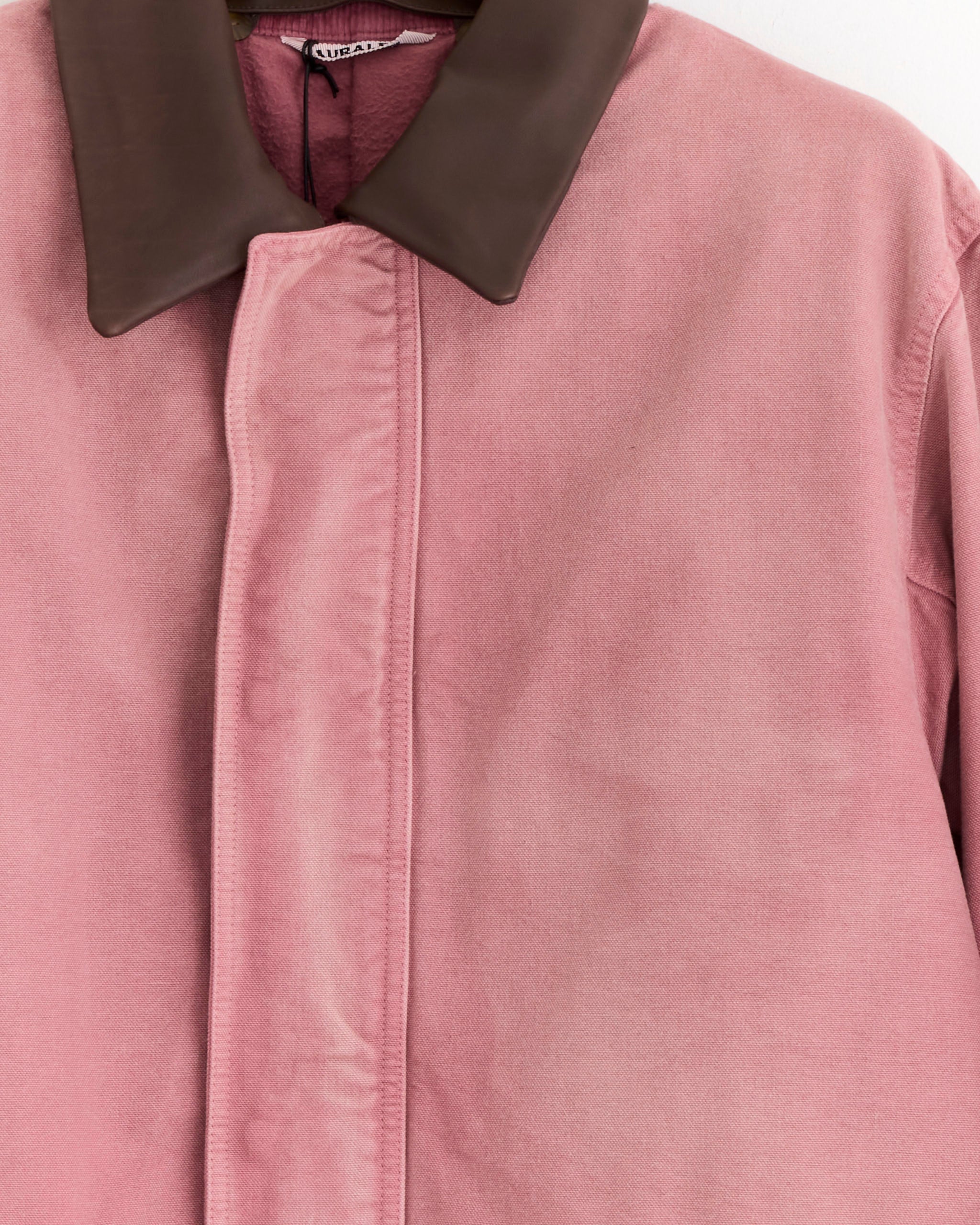 A close-up of the Auralee Dyed Duck Blouson in Faded Burgundy, made in Japan from soft organic cotton, featuring a dark brown collar, concealed front placket, and a gentle fabric texture.