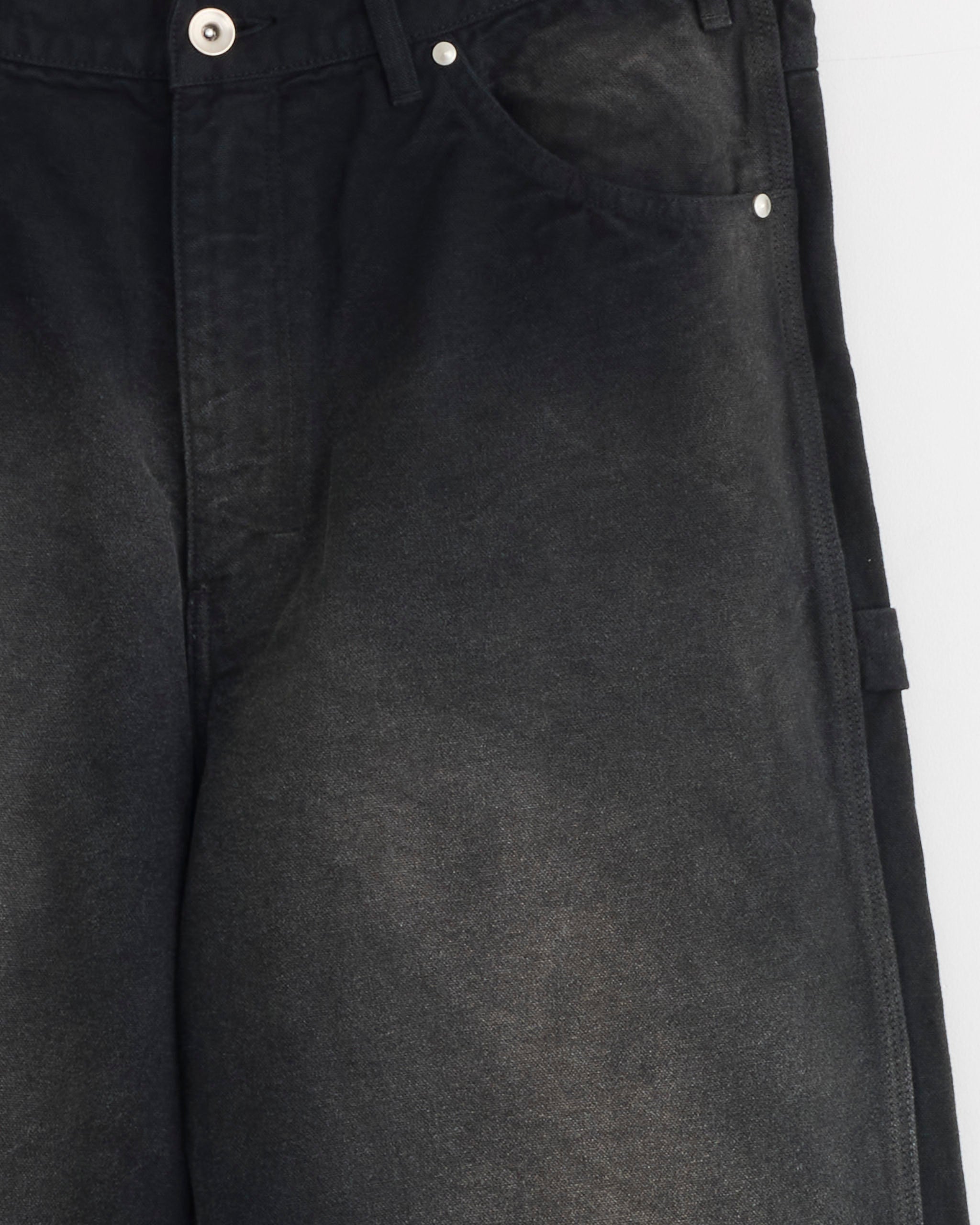 Close-up of the Auralee Dyed Duck Painter Pant in Faded Black, featuring organic cotton duck fabric with a subtle vintage look. Highlights include the waistband, button, front pocket, and upper thigh against a plain white background.