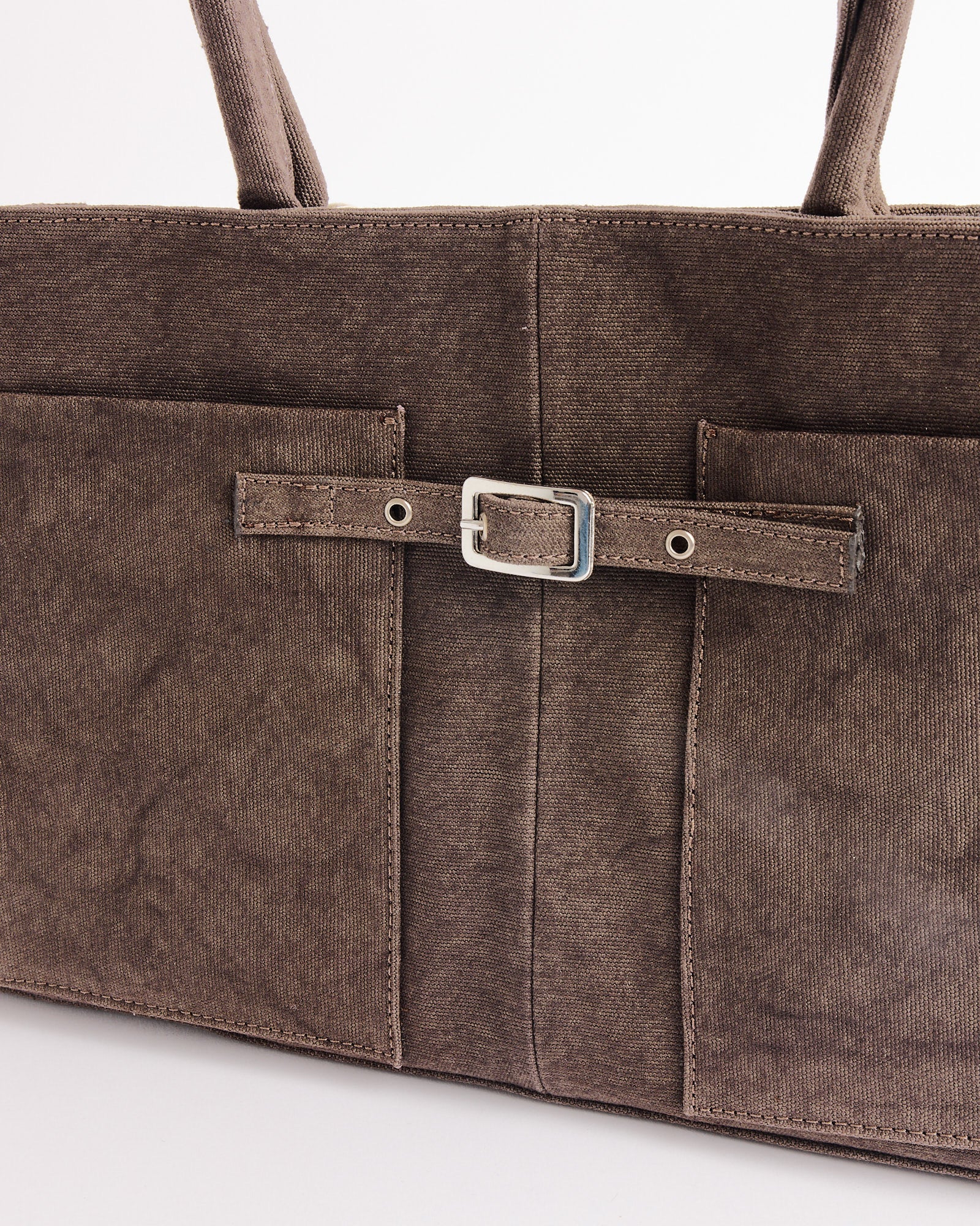 A close-up of the Annamaria Canvas Bag by Gimaguas, showcasing two front pockets and a decorative strap with a silver buckle. The structured cotton bag features sturdy handles and visible stitching.