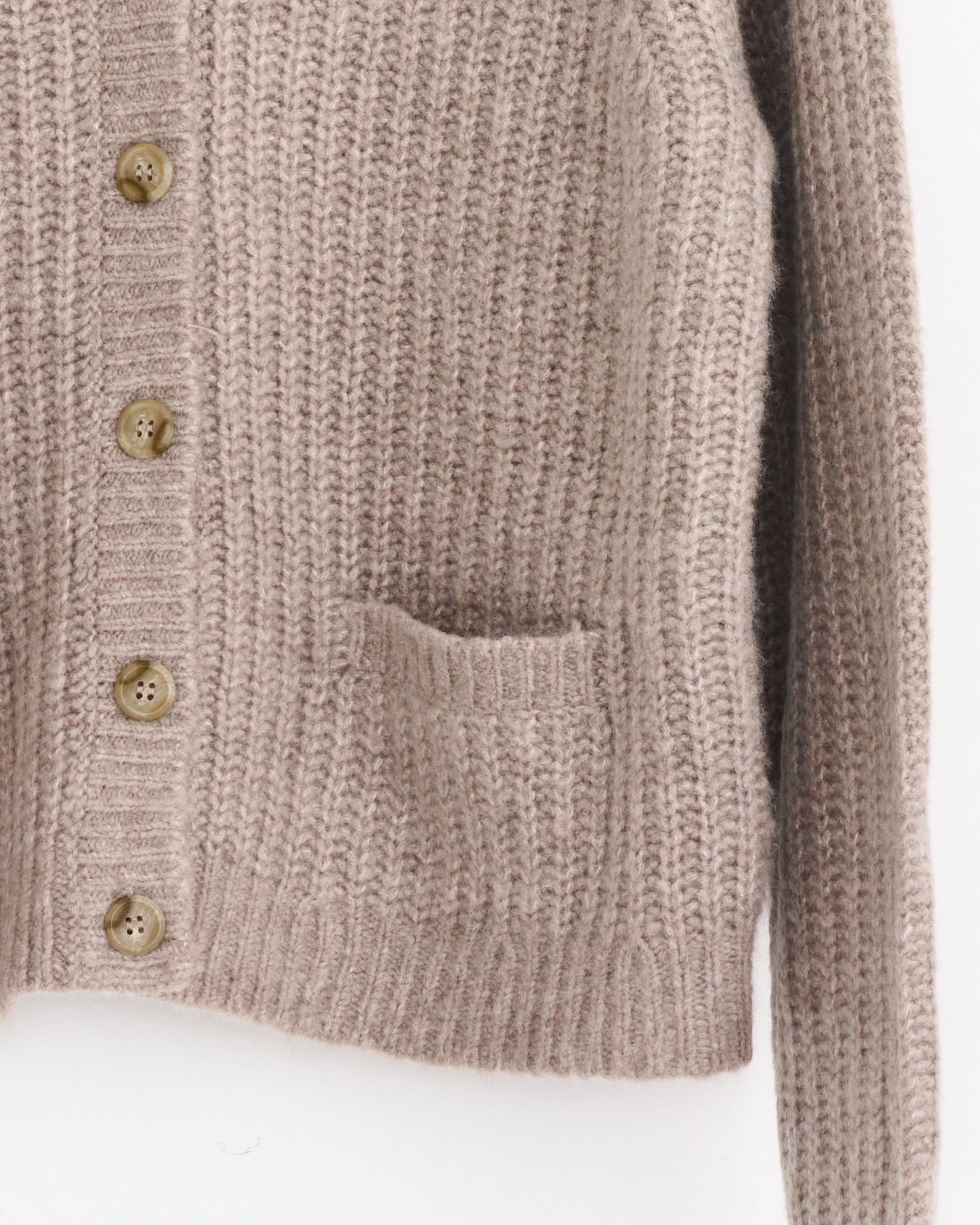 Close-up of the Hansel From Basel Cashmere Alden Cardigan in Mink, showing light brown knit fabric with a small front pocket and brown buttons. Only one sleeve and part of the torso are visible against a white background.
