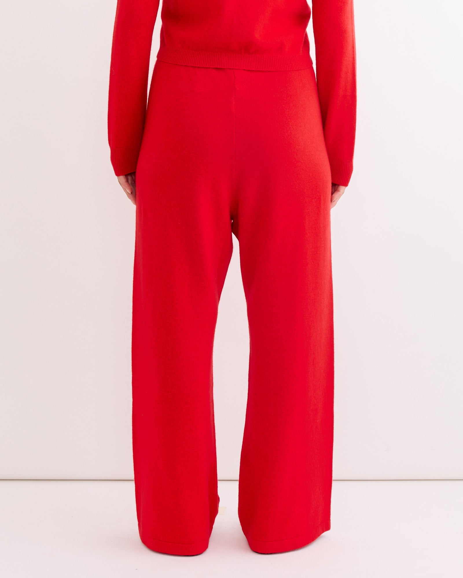 A person models the Hai Alfred Trouser in Red, paired with a matching red long-sleeve top, photographed from the back against a plain white background.