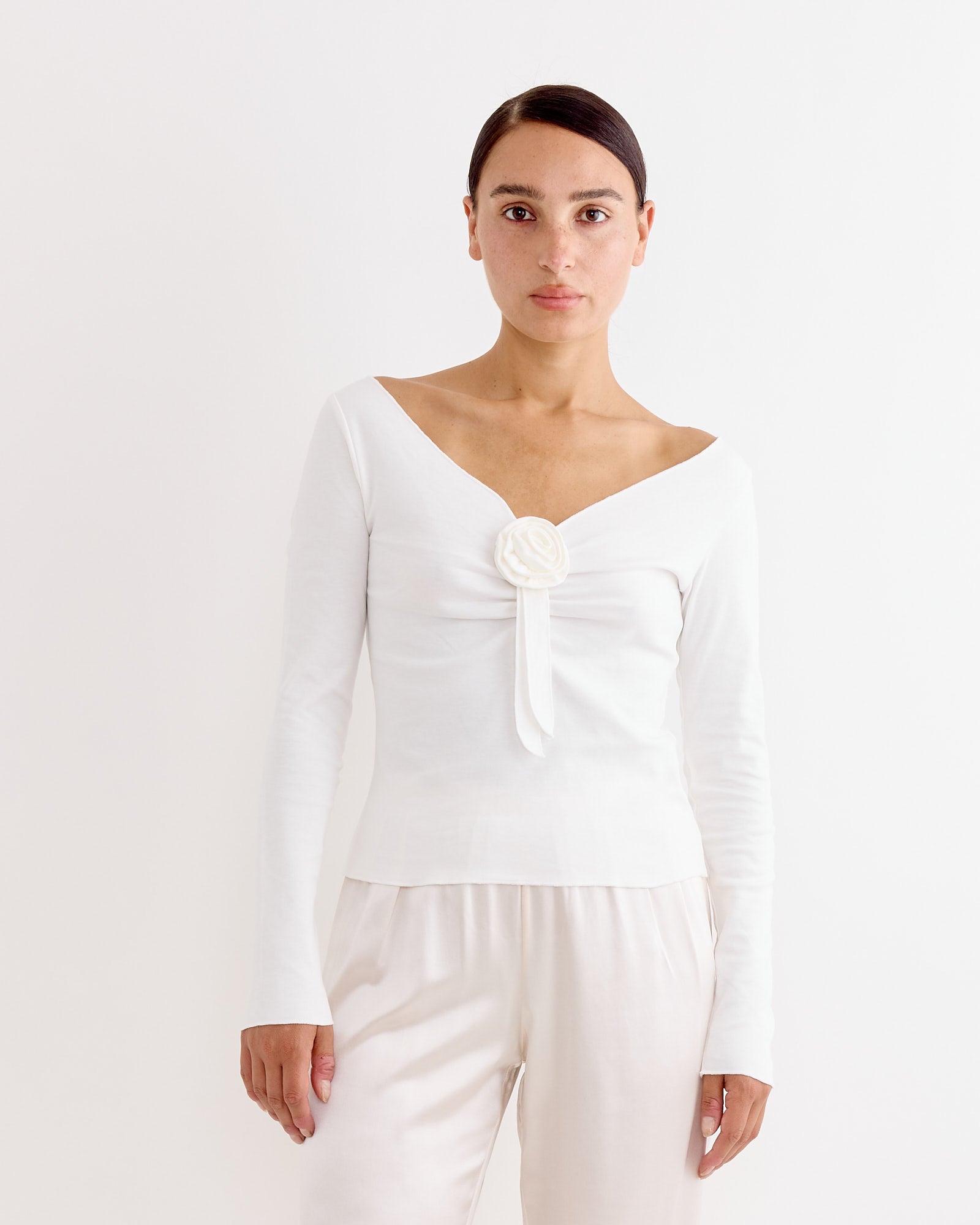 A woman in a long-sleeve v-neck Gretchen Tee in White by Hai, crafted from organic cotton jersey.