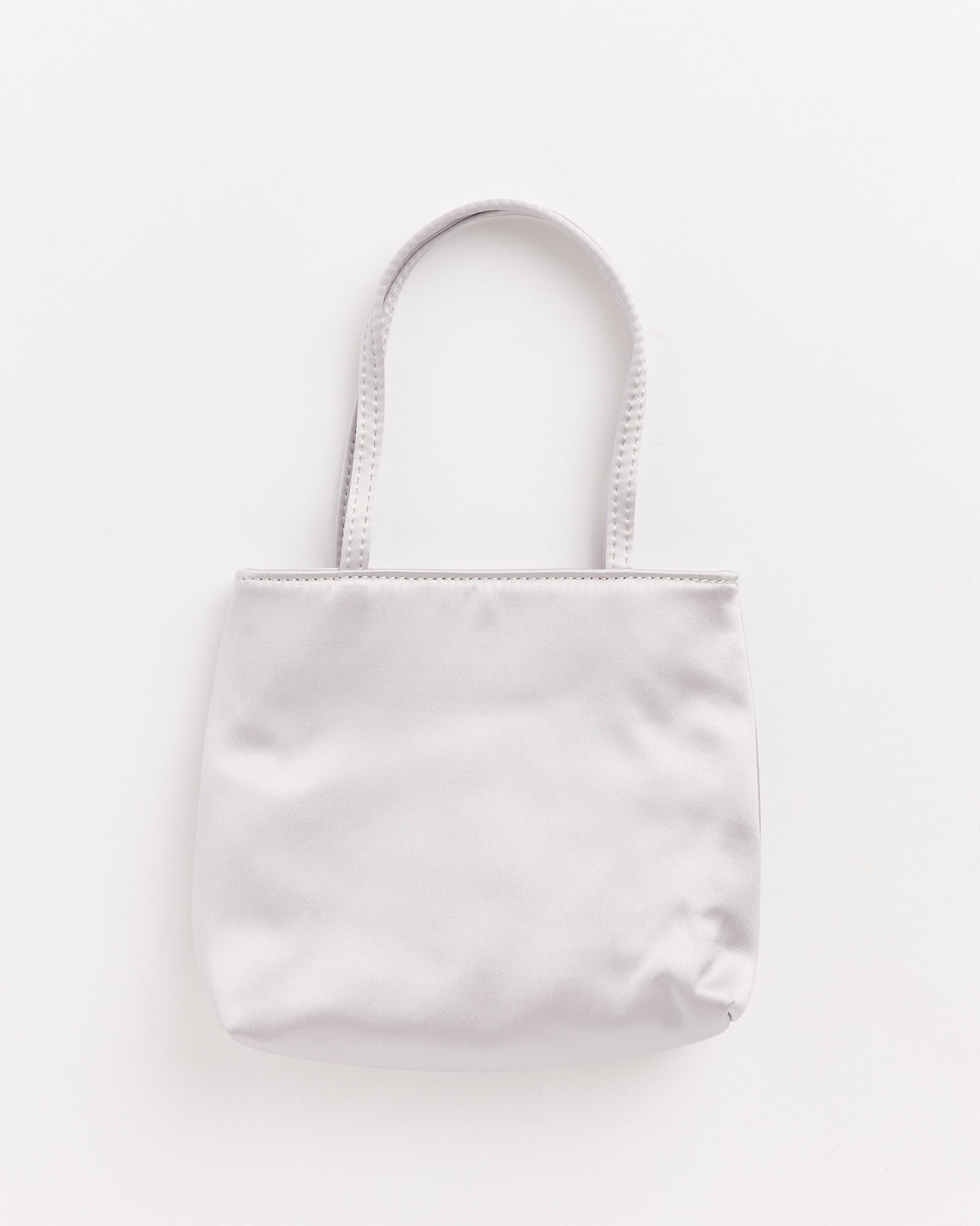 A simple Hai Little Silk Bag in Silver with two handles, photographed against a white background. The smooth fabric bag is unadorned, with a slight wrinkle at the bottom corner.