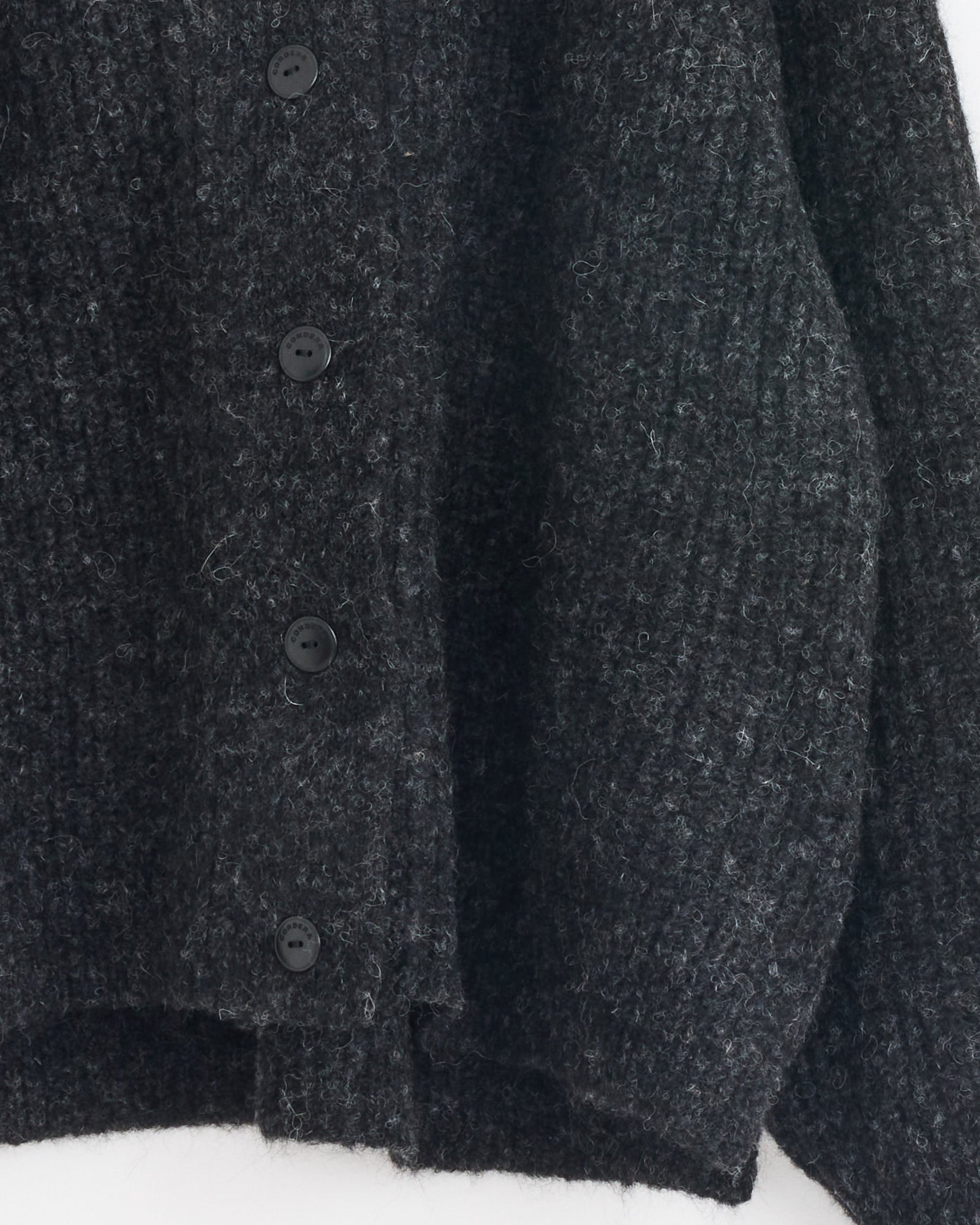 A close-up of the Cordera Baby Alpaca Cardigan in Anthracite, featuring a ribbed knit texture and four black buttons, made in Spain.