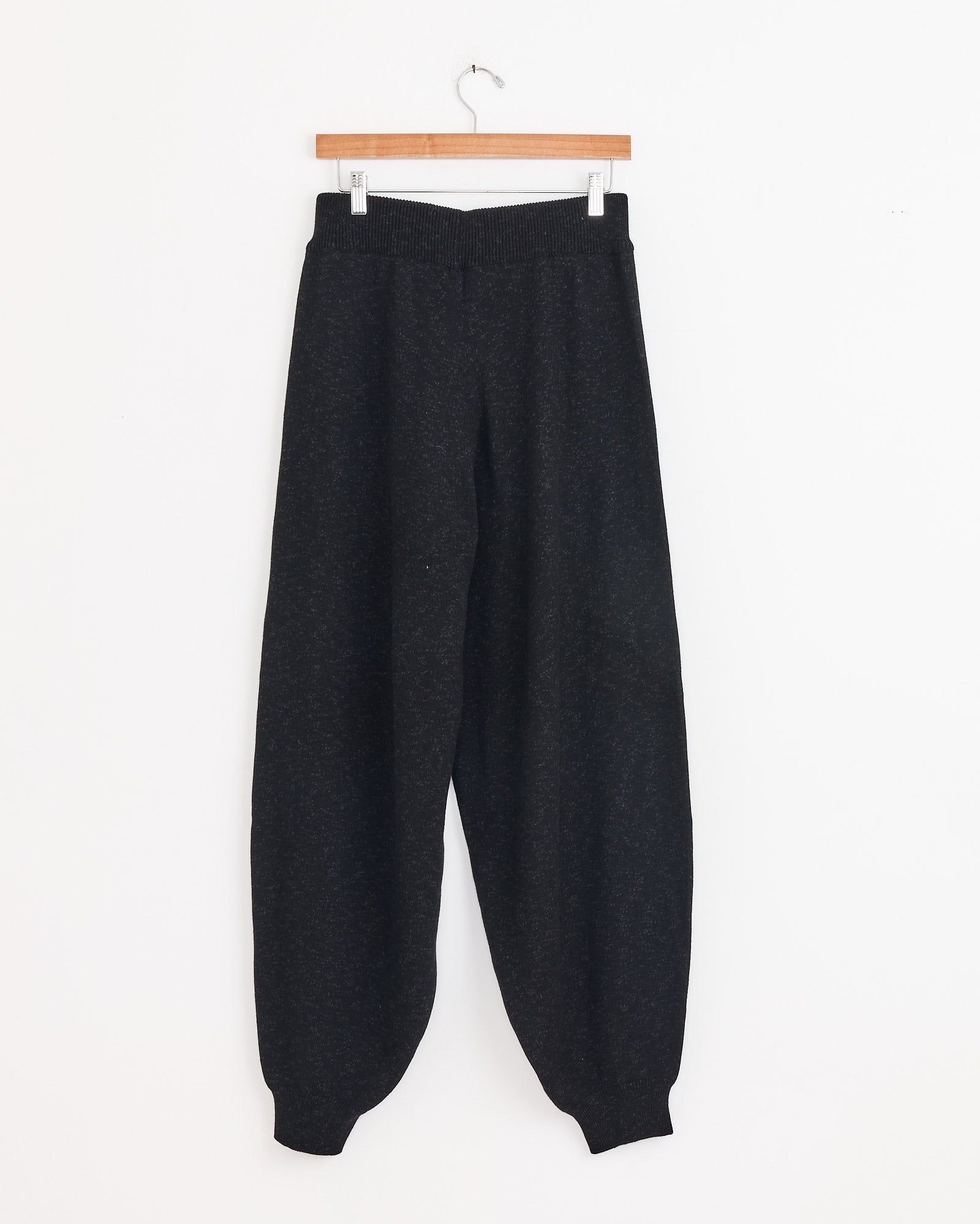 The Cordera Flecked Cotton Pant in Anthracite features a loose fit with an elastic waistband and cuffs, shown here on a wooden hanger against a white wall—ideal for relaxed everyday style.