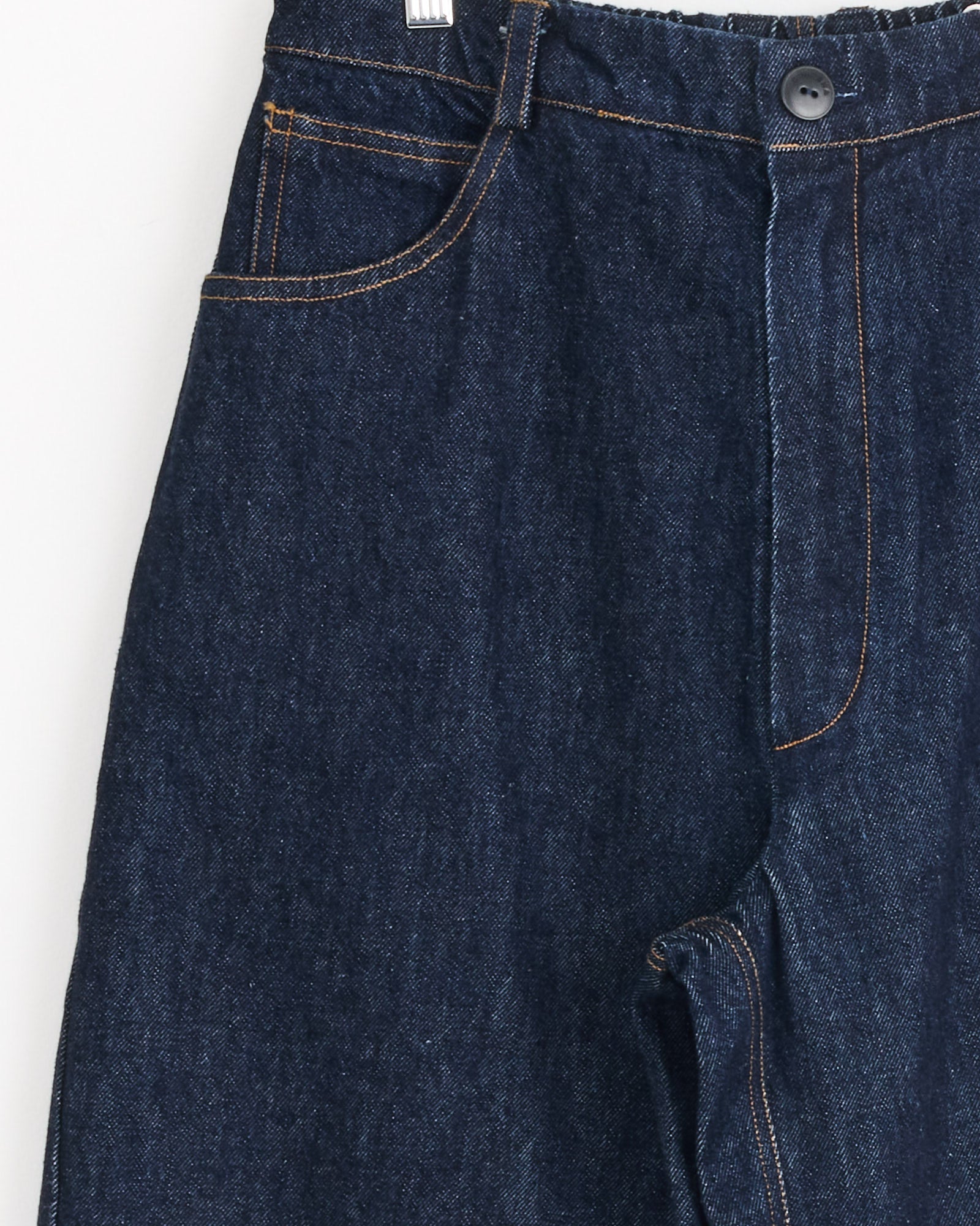 Close-up of Cordera's Denim Straight Pant in Indigo, featuring orange stitching, a front pocket, belt loop, high-rise waistband, and black top button. Made in Spain.
