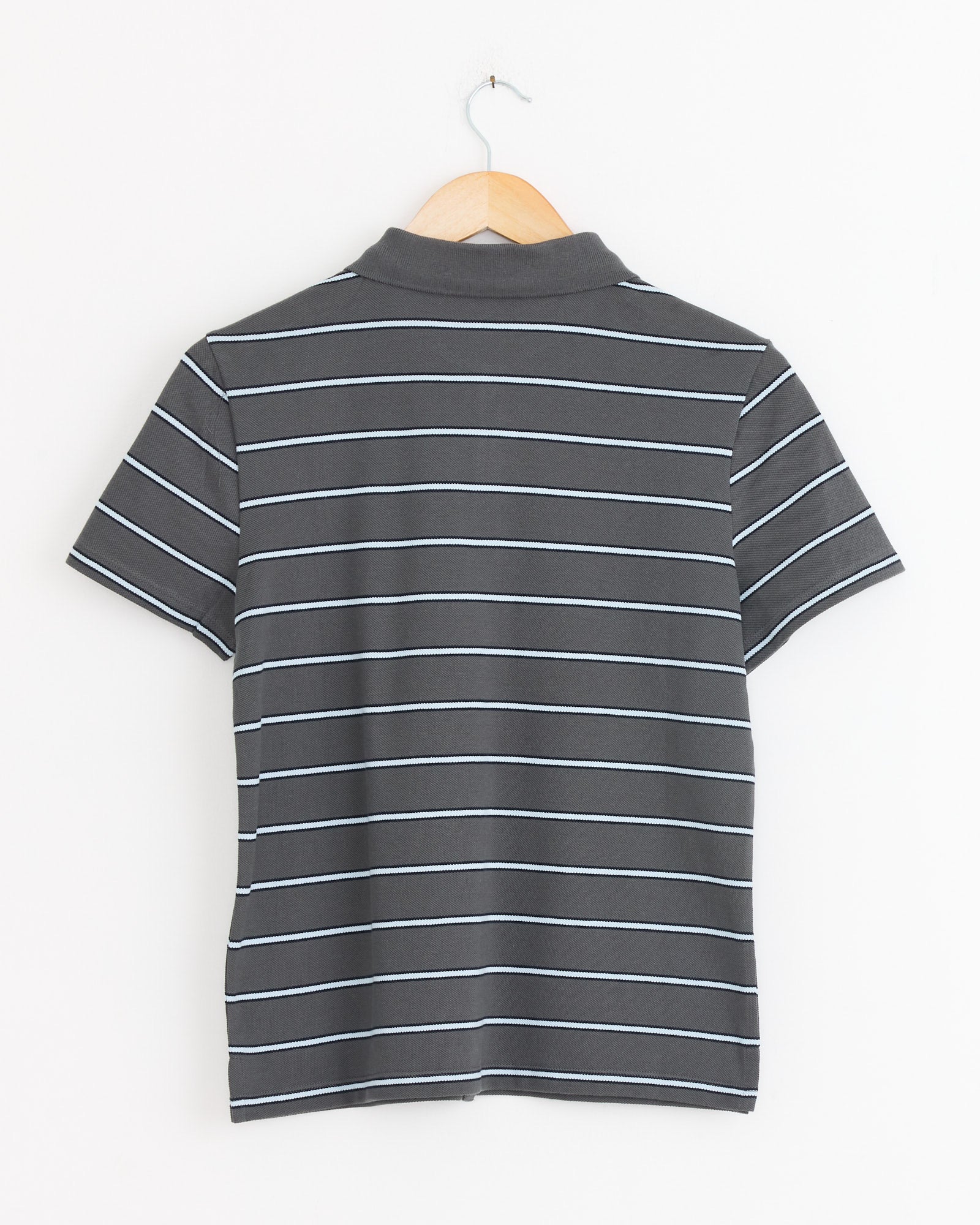 The Julieta Polo in Grey by Paloma Wool, featuring short sleeves and white stripes on soft piqué cotton, is displayed from the back on a wooden hanger against a plain white background.