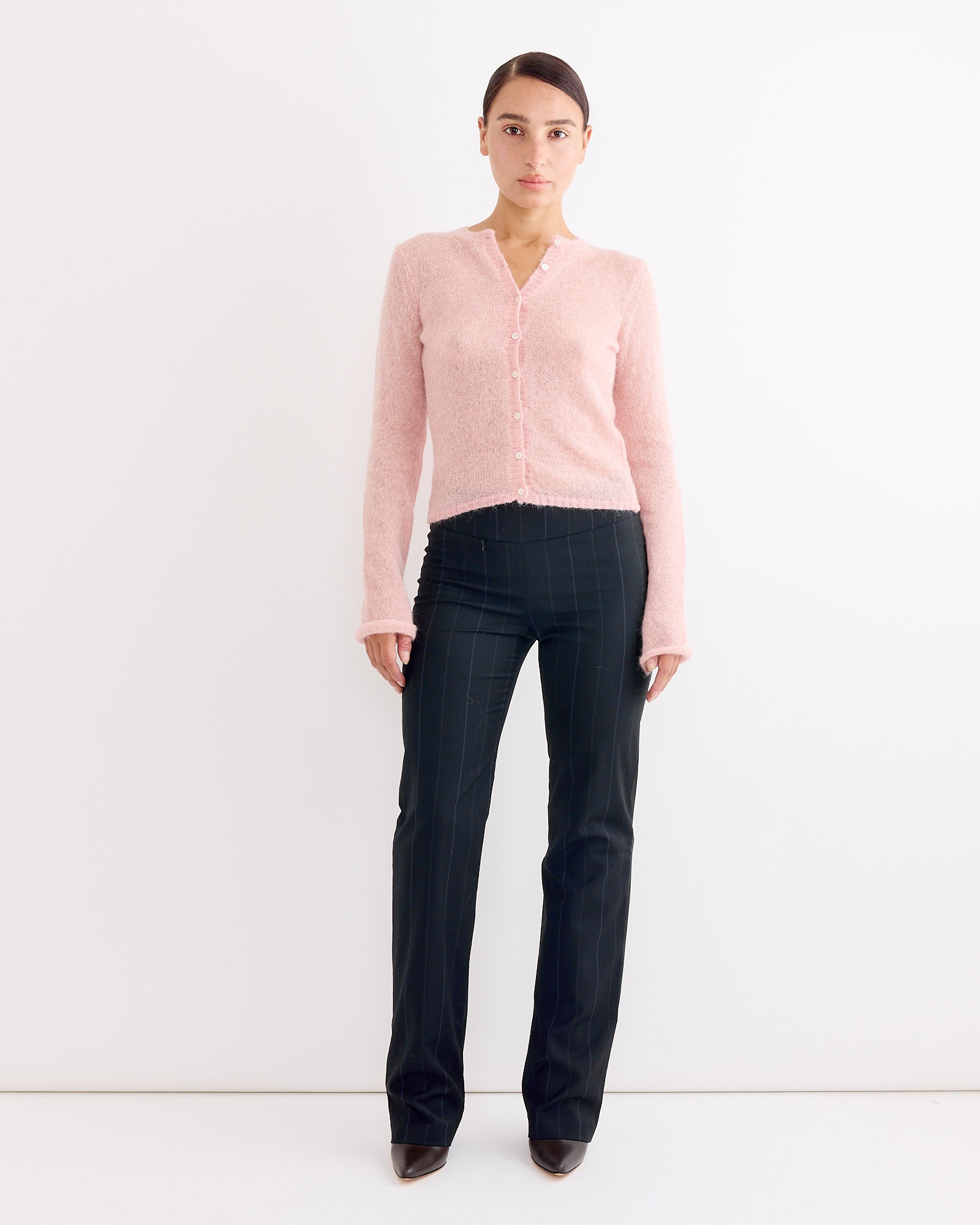A woman stands before a white wall, wearing Paloma Wool's Saba Pant in Blue, featuring a low-rise silhouette.