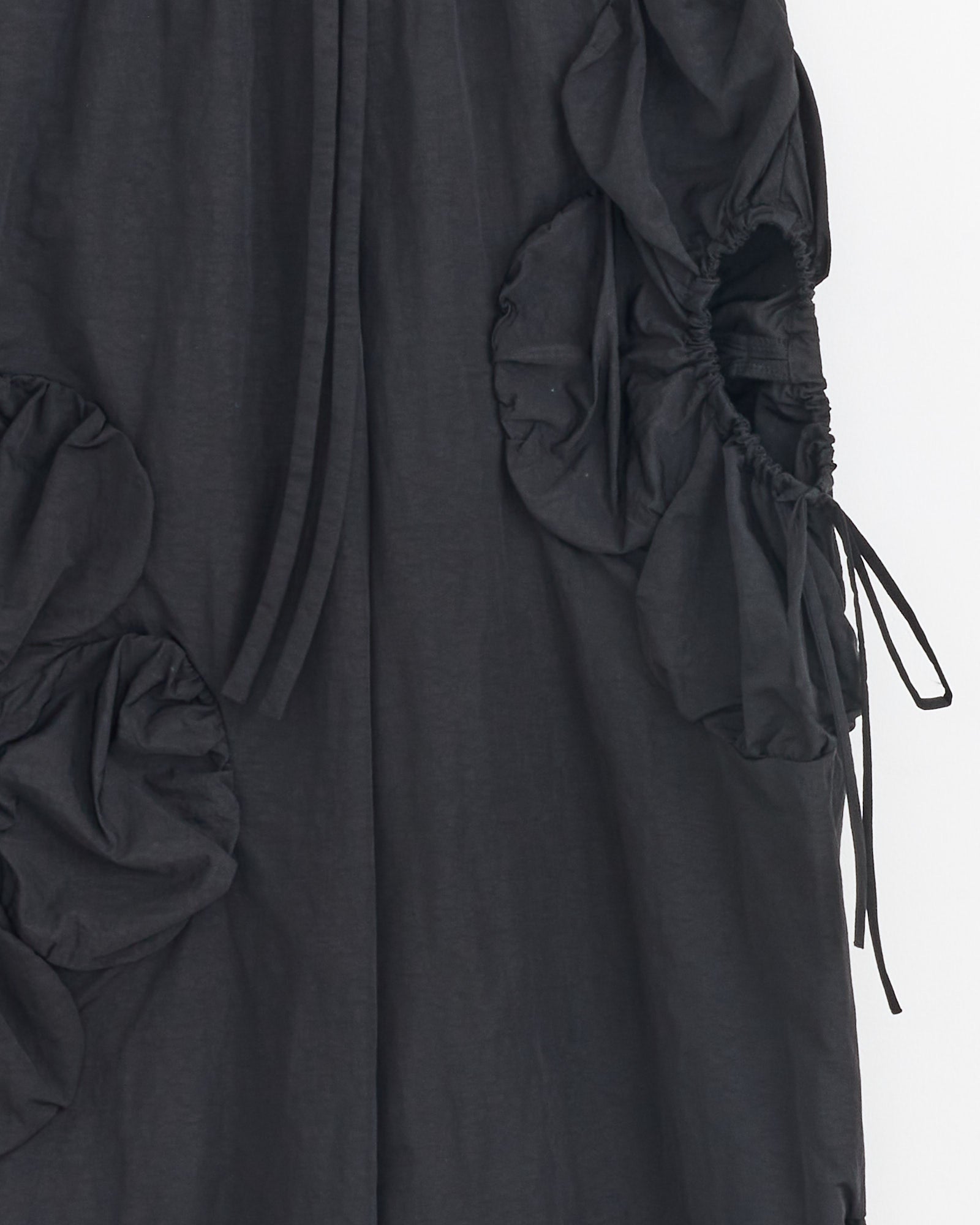 Close-up of the J. Kim Flower Pant in Black, showcasing gathered ruched fabric and drawstring ties that form sculptural, flower-like shapes on a smooth background.