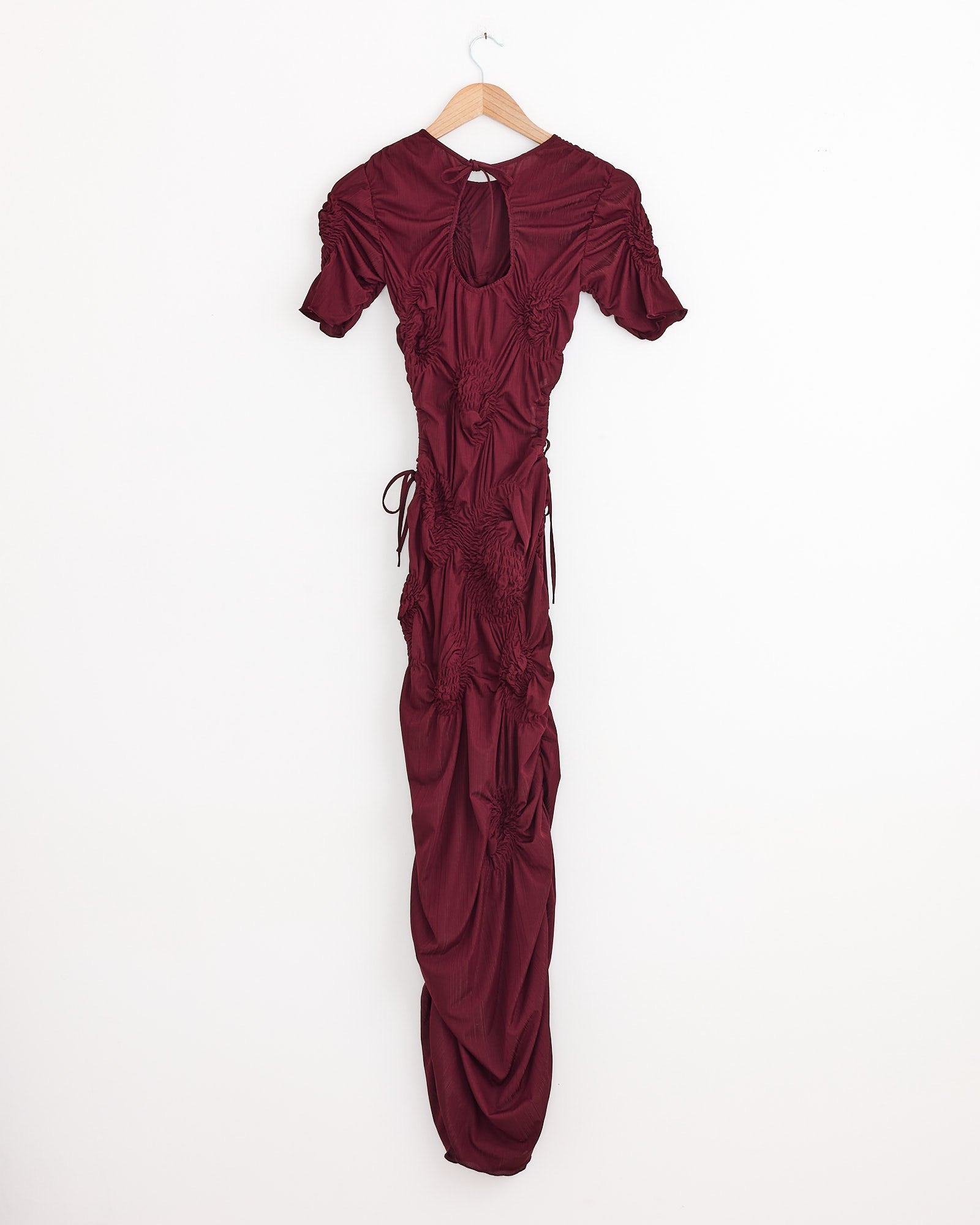 A long, short-sleeved Markiza Dress in Burgundy by J. Kim hangs on a wooden hanger against a plain white background.