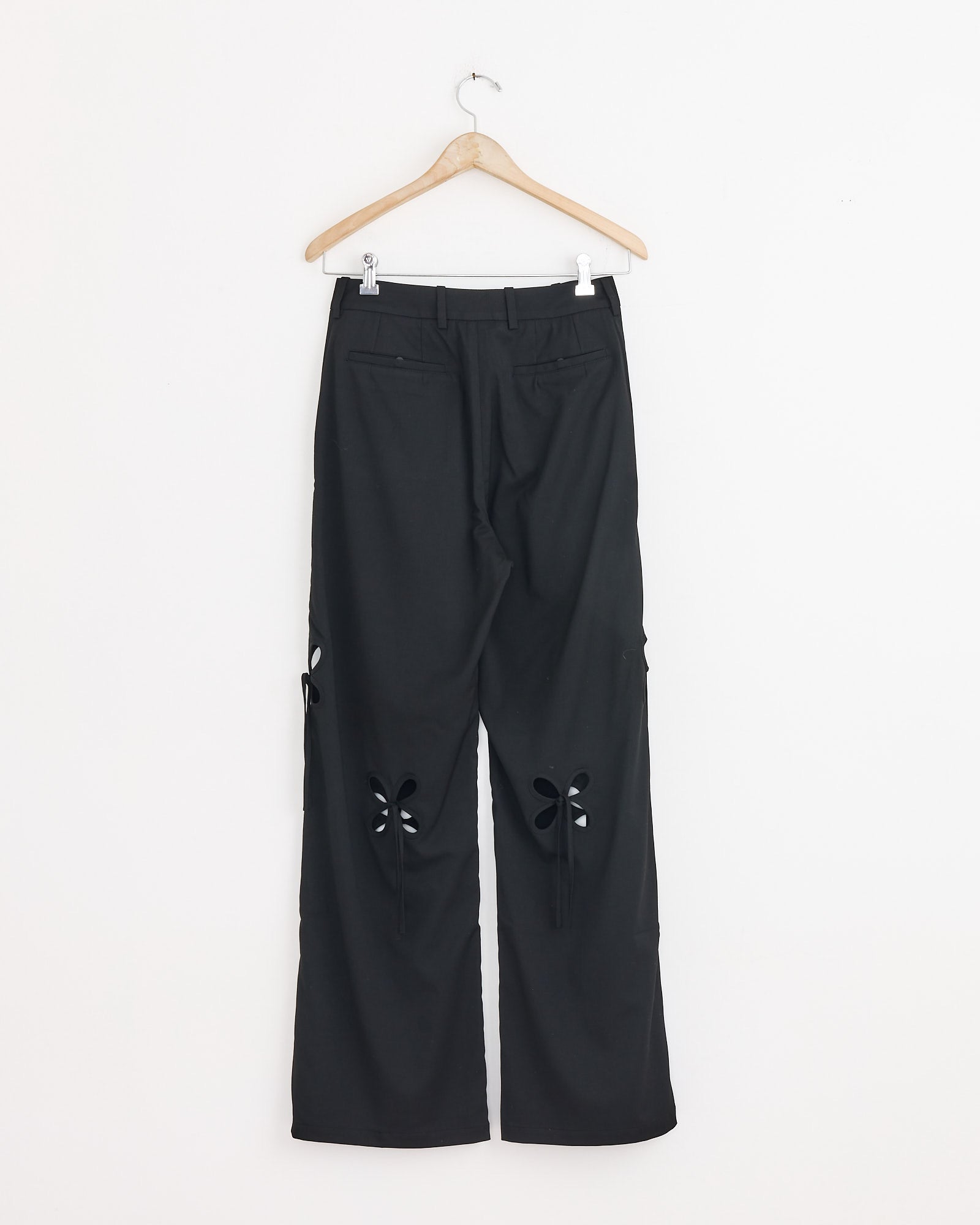 The Petal Suiting Trouser in Black by J. Kim is crafted from pure wool, featuring distinctive cut-out flower designs on the back of both legs below the knees for a unique tailored silhouette.